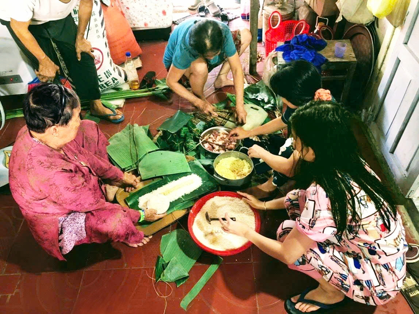 Bà tác giả ngồi gói bánh tét cùng con cháu vào ngày tết 