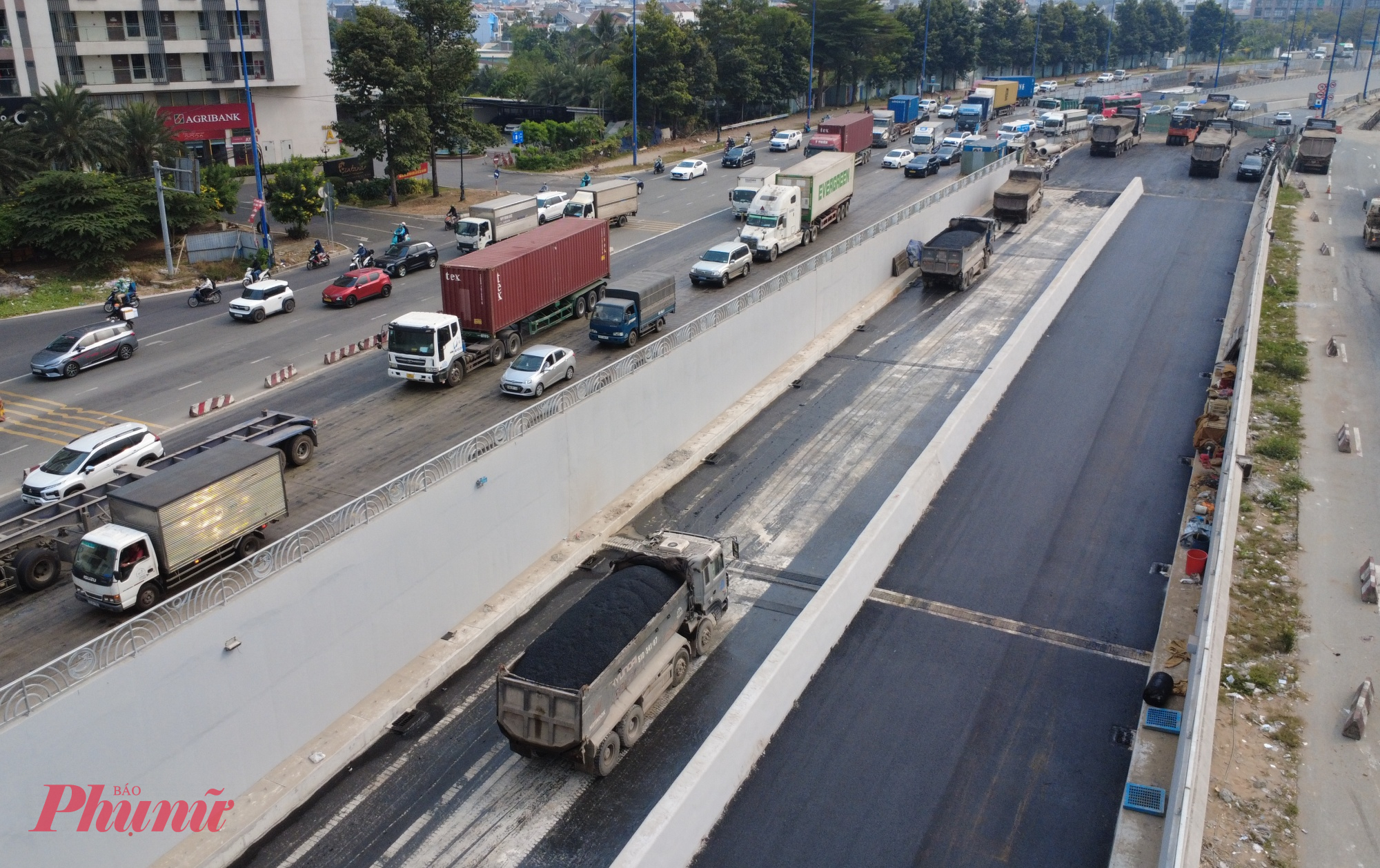 Nhiều xe ben chở nhựa đường tiến vào hầm chui để thi công thảm nhựa.