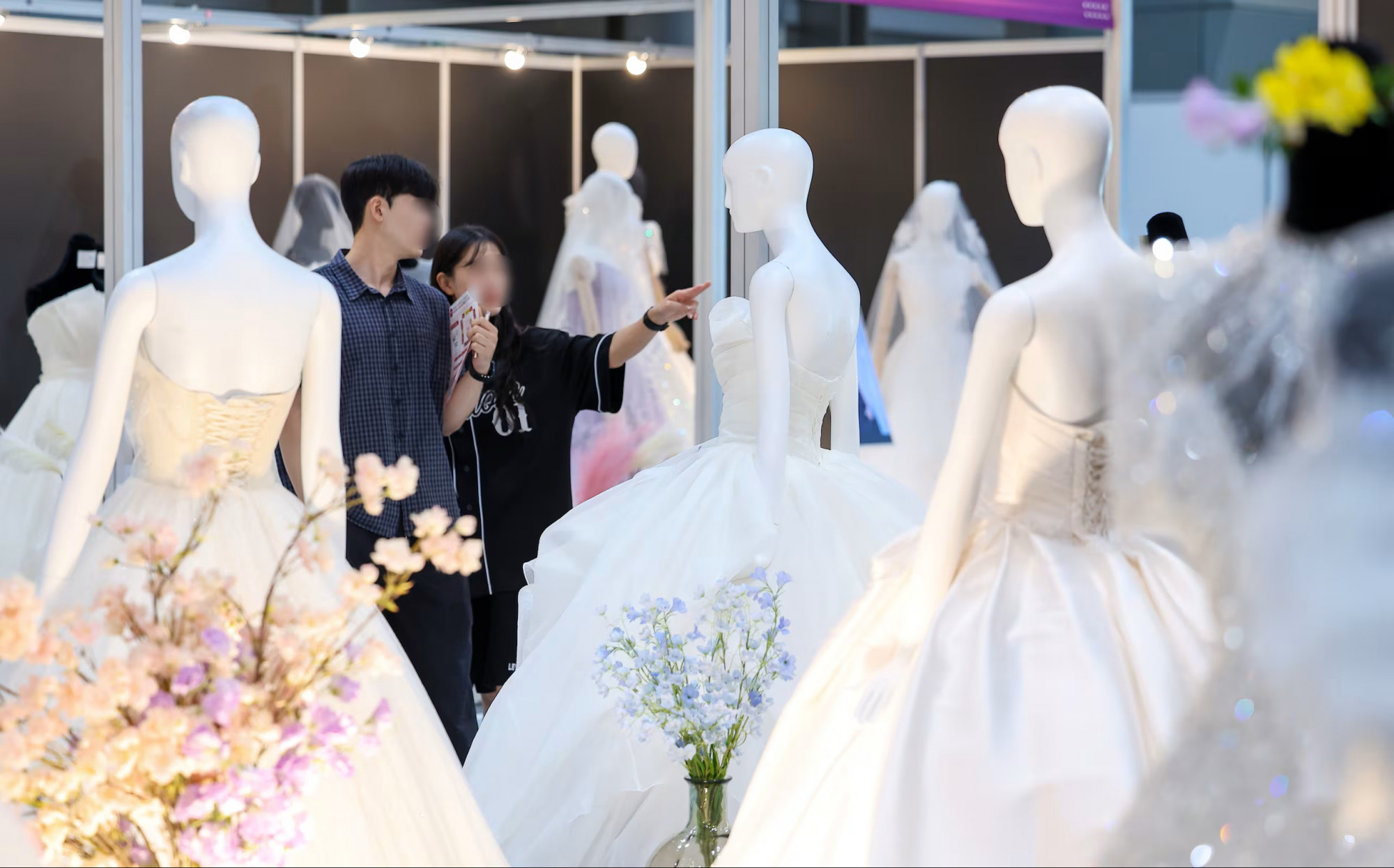 Một cặp đôi đang xem xét những mẫu váy cưới được trưng bày tại Hội chợ cưới WedExpo mùa thu 2025 tại quận Gangnam, Seoul - Ảnh: News1