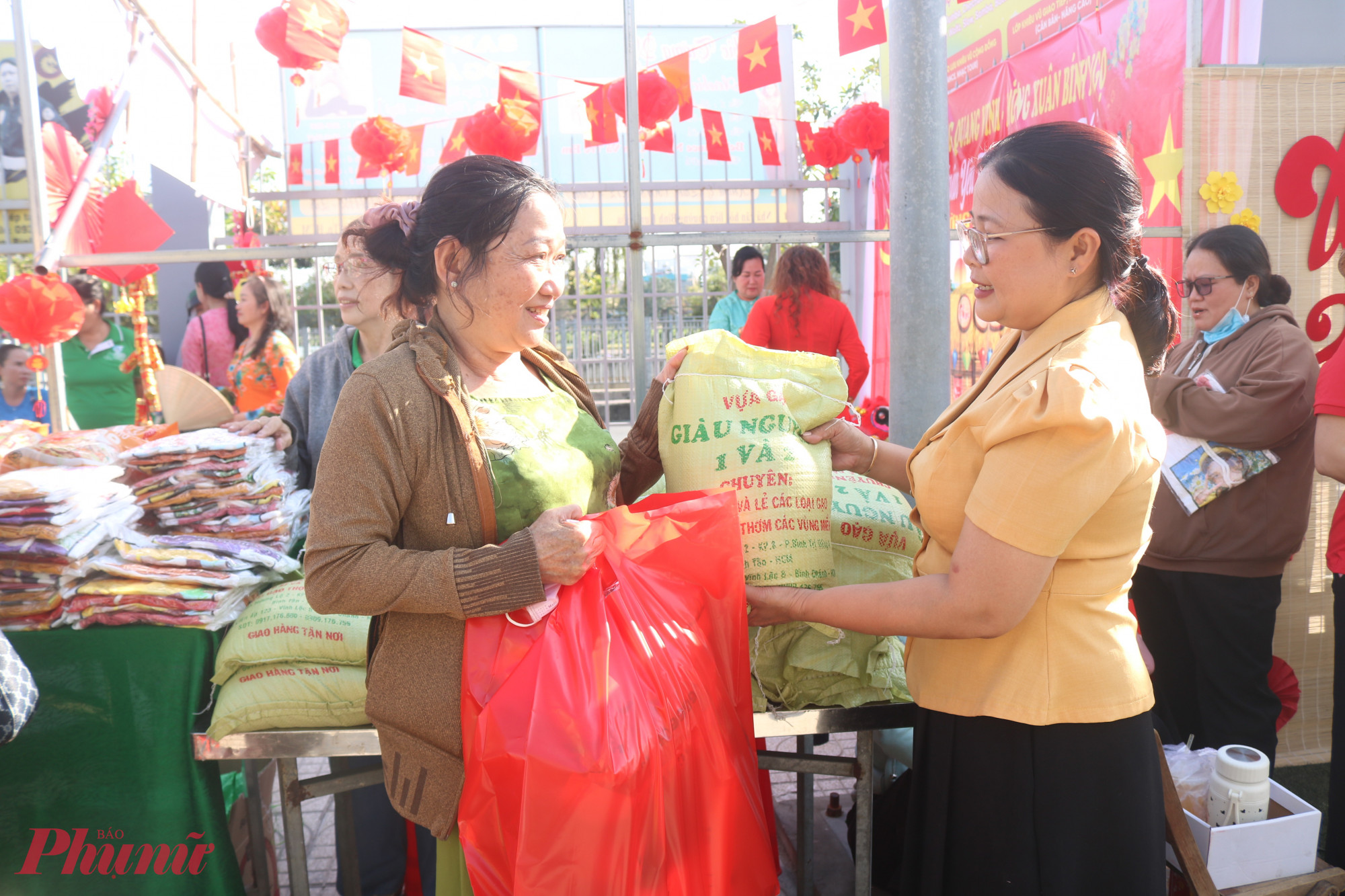 Bà Nguyễn Thị Minh Hậu – Phó chủ tịch Ủy ban MTTQ Việt Nam phường Bình Hưng Hòa, Chủ tịch Hội LHPN phường (bìa phải) trao quà từ gian hàng tết xưa cho các chị em - Ảnh: Mẫn Nhi