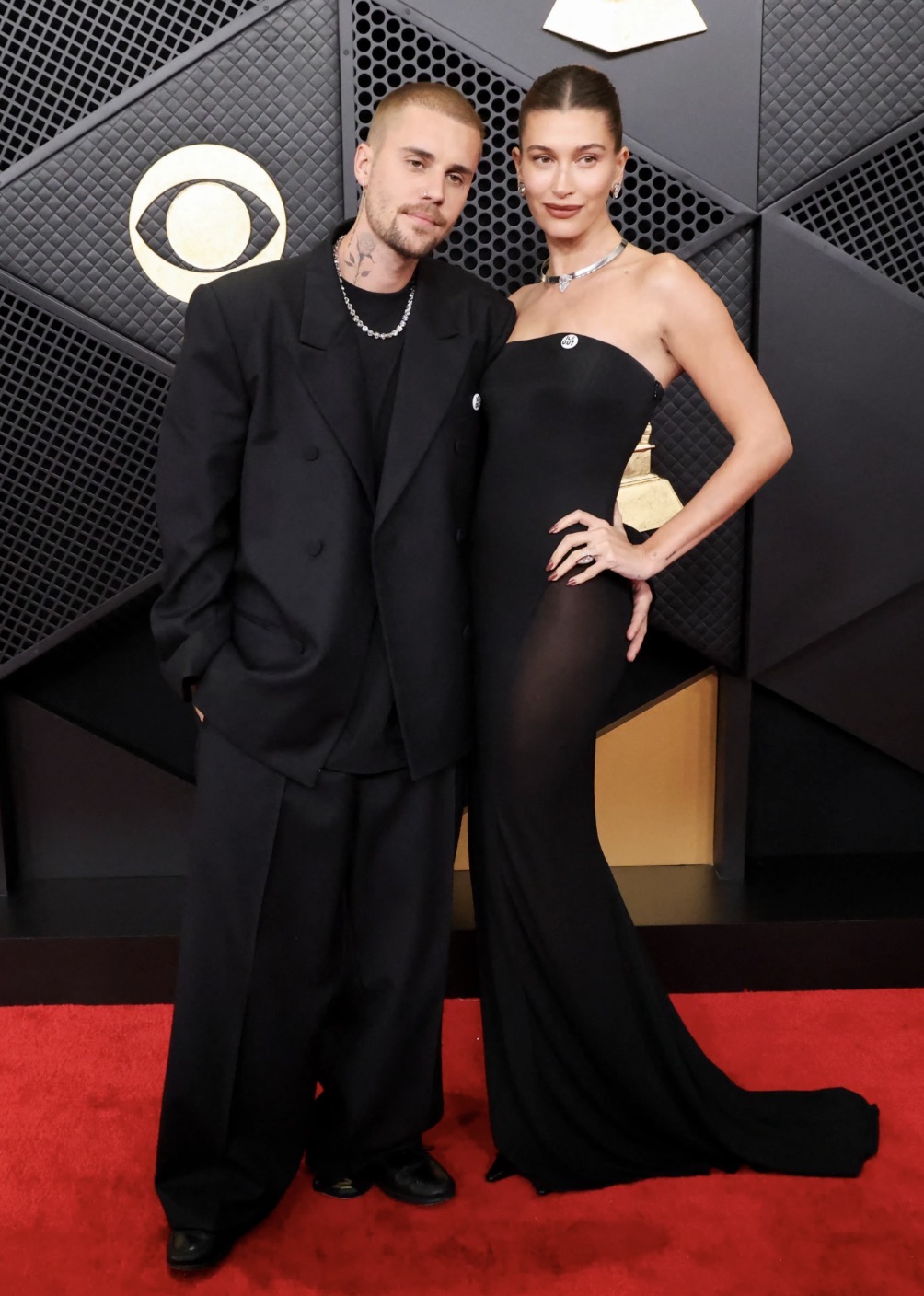 Vợ chồng Justin Bieber toát lên tinh thần thời trang tối giản nhưng đầy khí chất. Nam ca sĩ chọn suit đen phom rộng, layering phóng khoáng cùng phụ kiện tối giản, tạo cảm giác ngẫu hứng và hiện đại. Hailey Bieber gây ấn tượng với đầm đen dáng quây cổ điển, đường cắt gọn gàng ôm sát cơ thể, tôn vẻ thanh lịch và quyến rũ. 