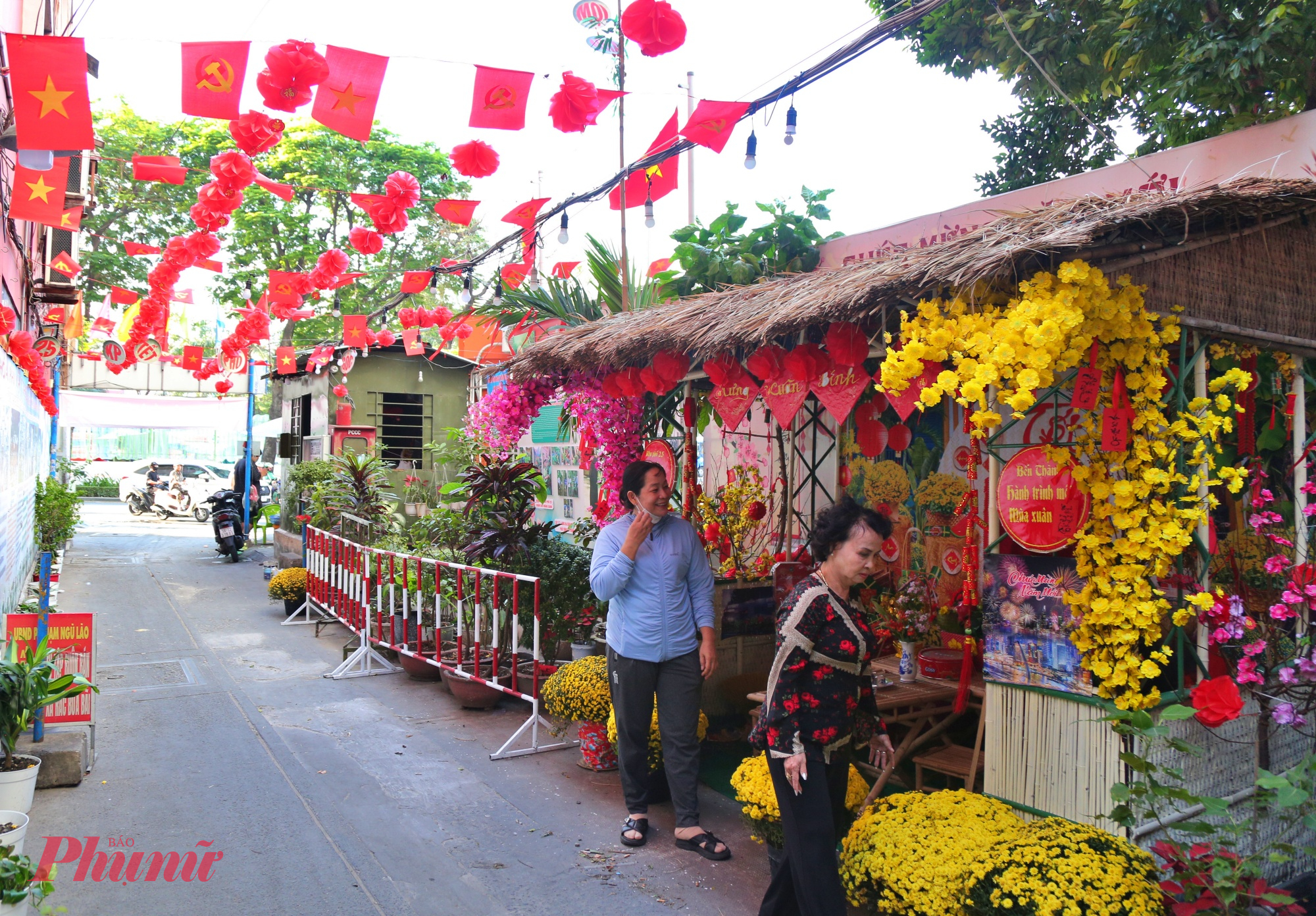 hẻm 353 Phạm Ngũ Lão, nơi sắc xuân ngập tràn ngay từ lối vào. Bà Trần Thị Thảo - Chi Hội trưởng Phụ nữ của khu phố cùng bà Nguyễn Thị Thanh Nga - Trưởng Ban Công tác Mặt trận khu phố thường xuyên có mặt để chăm sóc hoa, chỉnh trang tiểu cảnh, giữ cho đường hoa mini luôn tươi mới, gọn gàng.