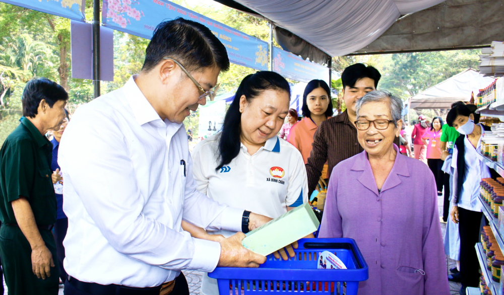Ông Nguyễn Thành Lợi (bìa trái) - Bí thư Đảng ủy, Chủ tịch HĐND xã Bình Chánh - thăm hỏi, động viên người dân tại “Phiên chợ 0 đồng” diễn ra hôm 29/1