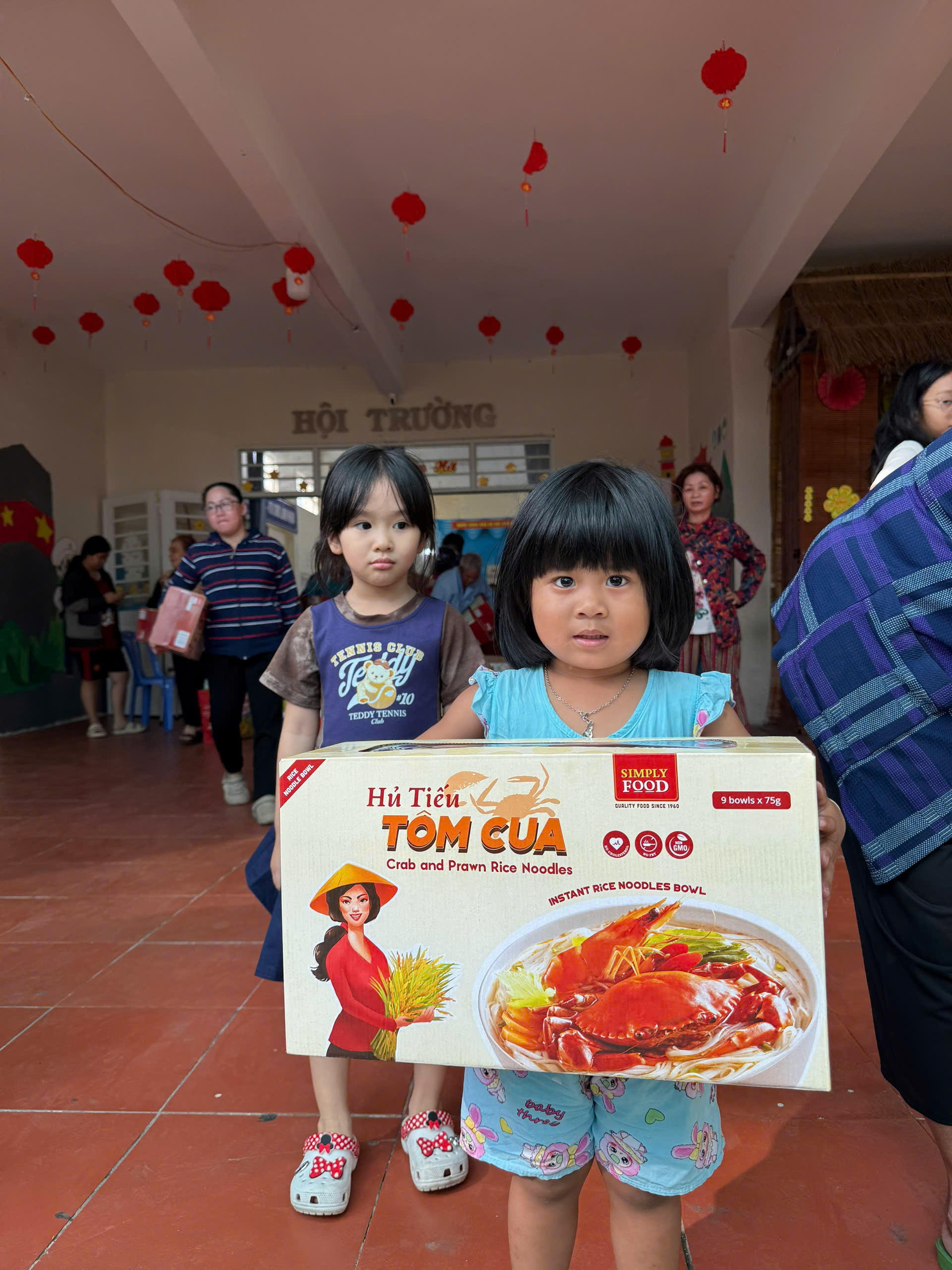 Niềm vui hiện rõ trên gương mặt các em nhỏ theo cha mẹ đến nhận quà, khi được ôm trên tay những hộp quà tết mới tinh, đầy màu sắc - Ảnh: Ngọc Thùy