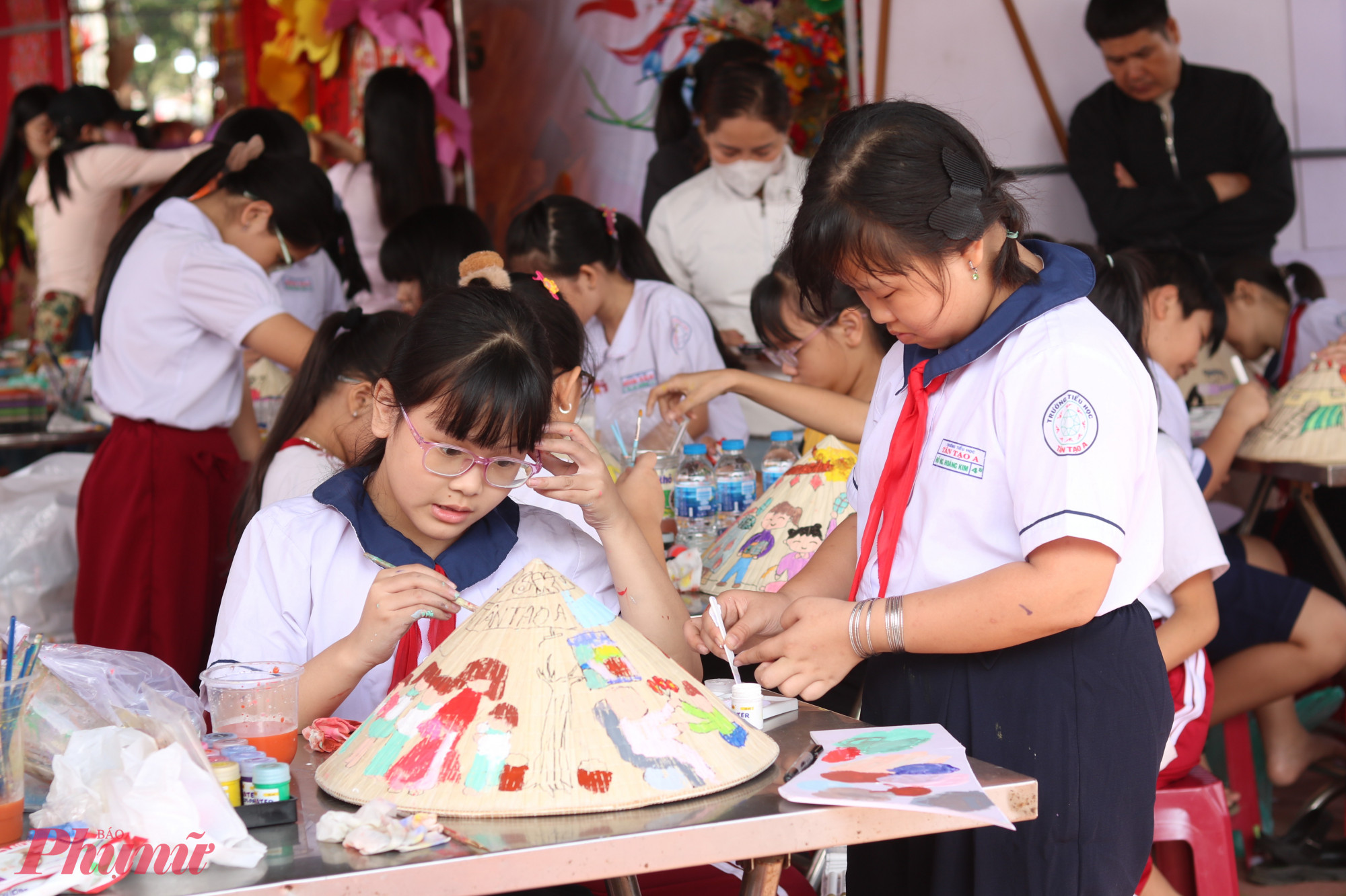 Các em học sinh chăm chú trang trí nón lá bằng những hình vẽ sinh động - Ảnh: Thảo Nguyên