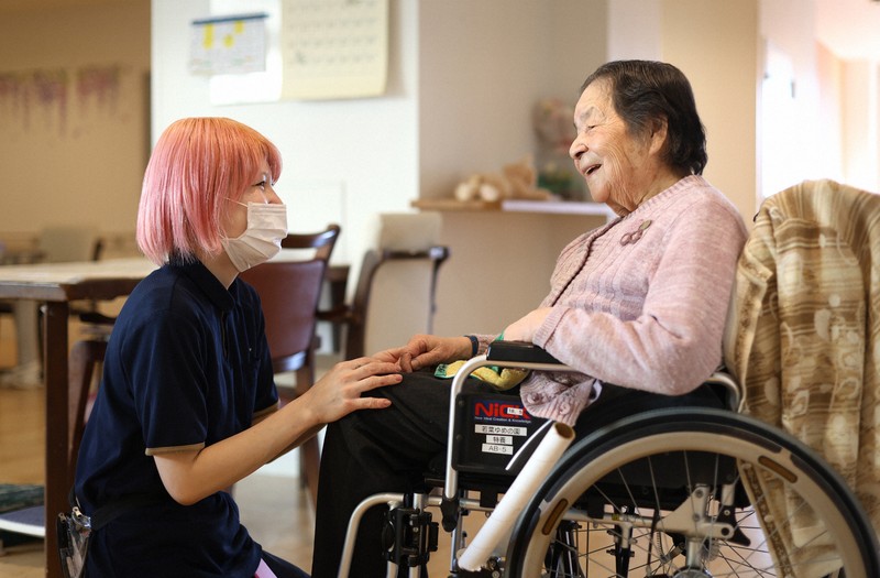 Yuna Kanasashi (bên trái), một người chăm sóc tại một viện dưỡng lão đặc biệt ở quận Itabashi, Tokyo, khoe mái tóc hồng của mình khi đang chăm sóc một cư dân.