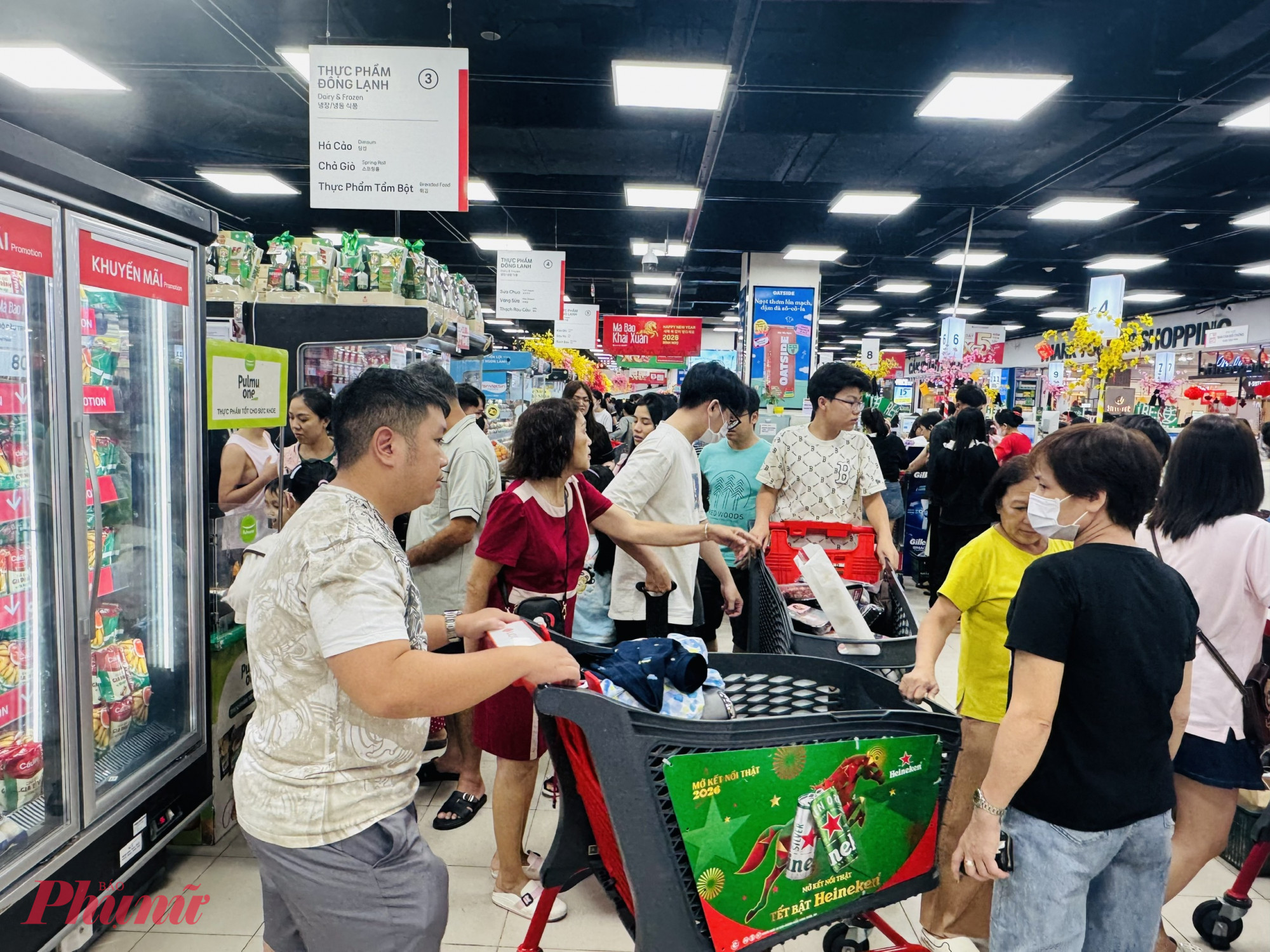 Tối ngày 7/2, Trung tâm thương mại Lotte Mart (phường Tân Hưng, TP.HCM) đông nghẹt khách đến mua sắm. Những người có xe đẩy phải di chuyển chậm rãi để tránh va chạm với người xung quanh