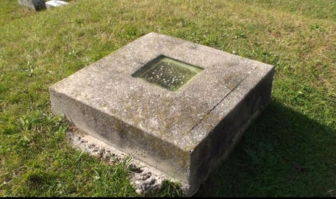 “Cơn ác mộng” bị chôn sống ám ảnh lịch sử một thời Một ngôi mộ cổ từ thế kỉ XIX với ô kính thủy tinh được lắp ở vị trí đầu quan tài, như một nỗ lực phòng ngừa nỗi sợ bị chôn sống của người xưa. Ảnh chụp tại nghĩa trang Evergreen, New Haven, bang Vermont, Hoa Kỳ. (Ảnh: Vermonter)