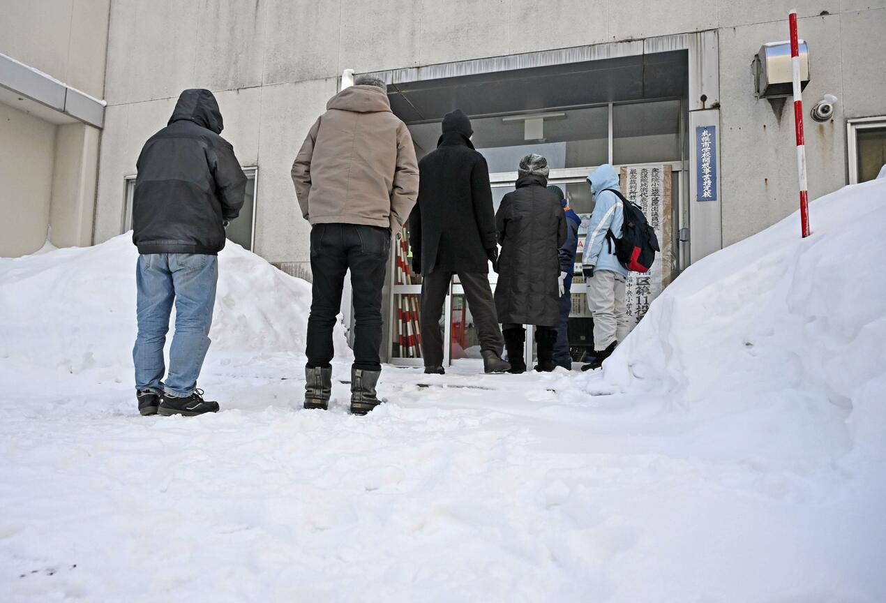 Người dân xếp hàng trong tuyết bên ngoài một điểm bỏ phiếu ở Sapporo để bỏ phiếu bầu cử Hạ viện vào ngày 8/2 - Ảnh: Kyodo