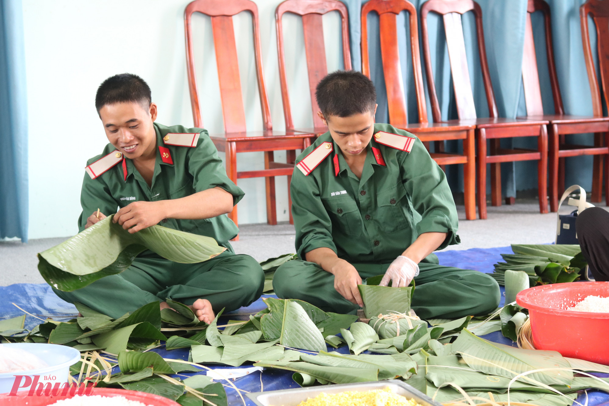 2 chiến sĩ của Lữ đoàn công binh hỗn hợp 279 chăm chú cắt lá dong và gói bánh chưng - Ảnh: Mẫn Nhi 