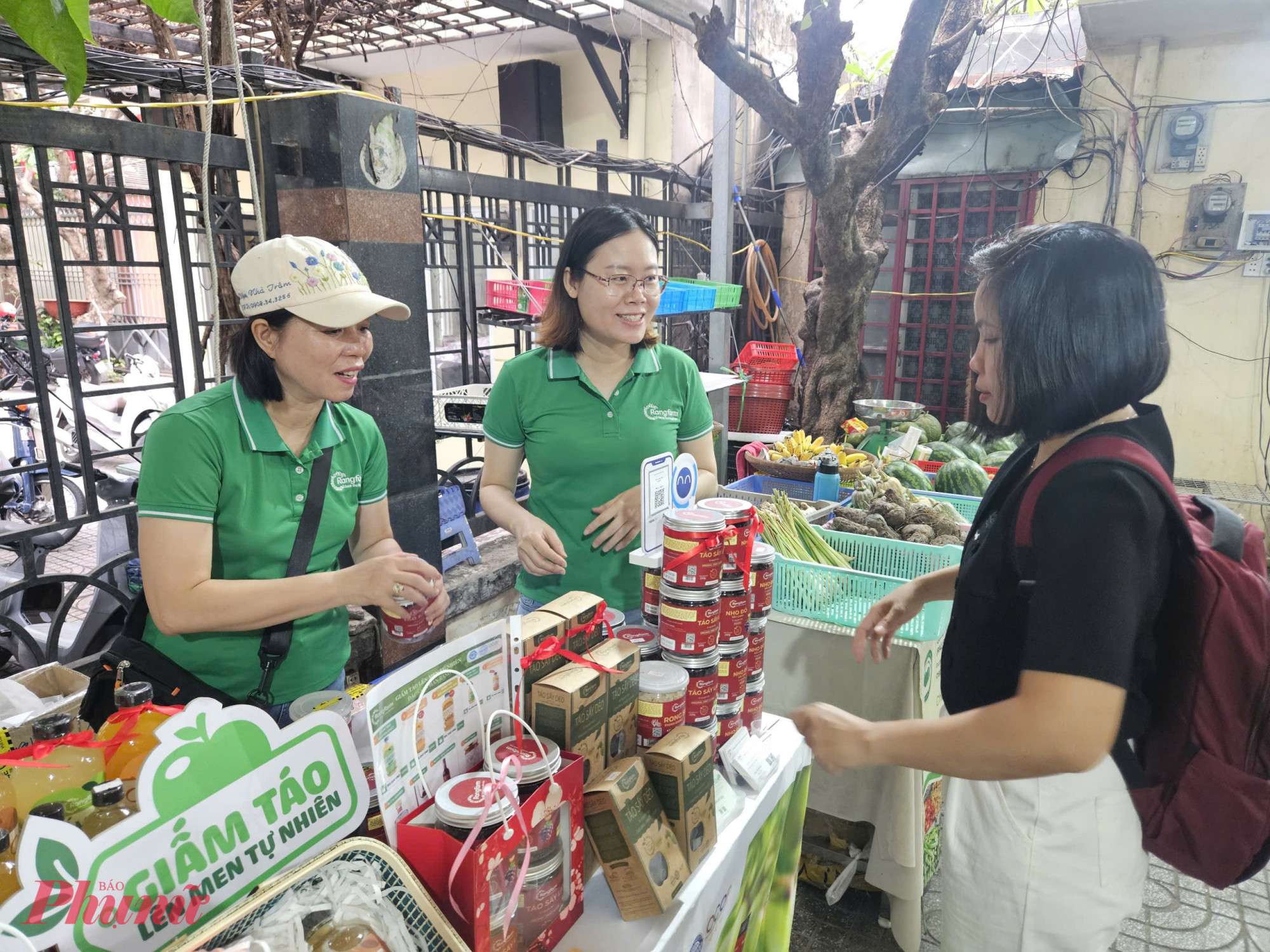 Không khí mua sắm nhộn nhịp tại gian hàng trái cây sấy, lên men tự nhiên ở Phiên chợ Tết Xanh – Quà Việt. Nhiều khách dừng lại nghe tư vấn, ăn thử sản phẩm trước khi quyết định mua.