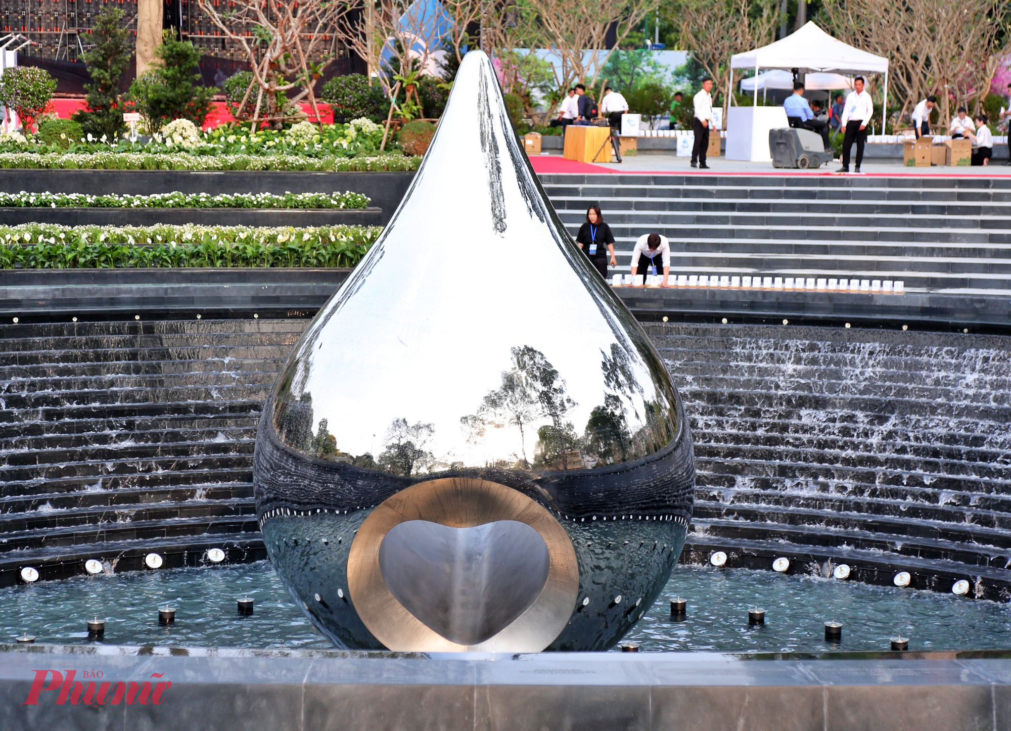 Bề mặt phản chiếu hình bóng người đứng quanh, gửi gắm thông điệp: nỗi buồn không của riêng ai, mà là ký ức chung được sẻ chia.