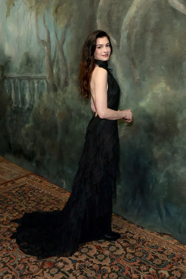 Diện bộ váy đen dáng dài, hở lưng tinh tế, Anne Hathaway ghi điểm với phong cách quyến rũ, cổ điển và đầy chất điện ảnh. Thiết kế tối giản nhưng tập trung vào đường cắt và phom dáng giúp tôn lên vẻ đẹp thanh thoát, đúng chuẩn phong cách thảm đỏ cao cấp.