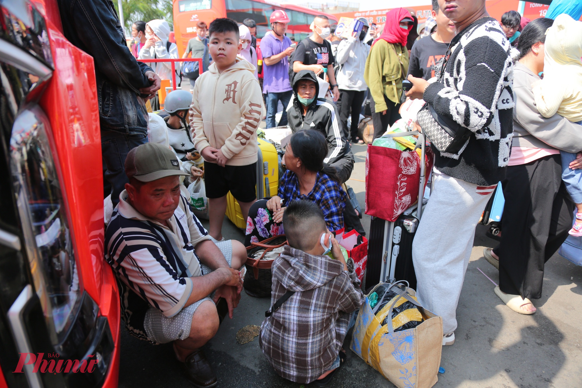 Nhiều gia đình có trẻ nhỏ, người lớn tuổi phải đội nắng, quạt tay liên tục giữa biển người đông nghịt. 