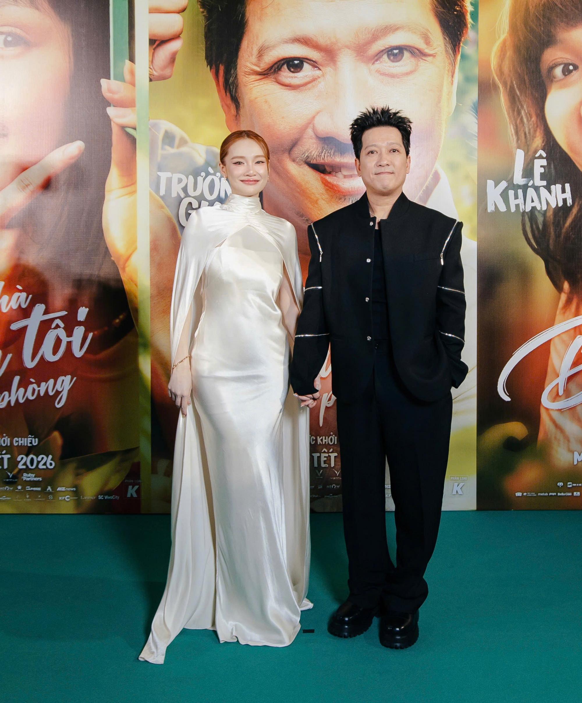 Nhã Phương và Trường Giang xuất hiện với phong cách thời trang trang nhã nhưng đầy khí chất. Nữ diễn viên nổi bật trong chiếc váy lụa trắng dáng dài, phom ôm nhẹ cùng phần choàng mềm mại, tạo cảm giác thanh thoát và nữ tính. Chất liệu óng ánh kết hợp gam màu trắng tinh khôi giúp cô toát lên vẻ sang trọng, hiện đại mà vẫn rất dịu dàng. Trong khi đó, Trường Giang lựa chọn bộ trang phục đen tối giản với thiết kế gọn gàng, đường cắt dứt khoát, mang đến hình ảnh lịch lãm và chững chạc. 