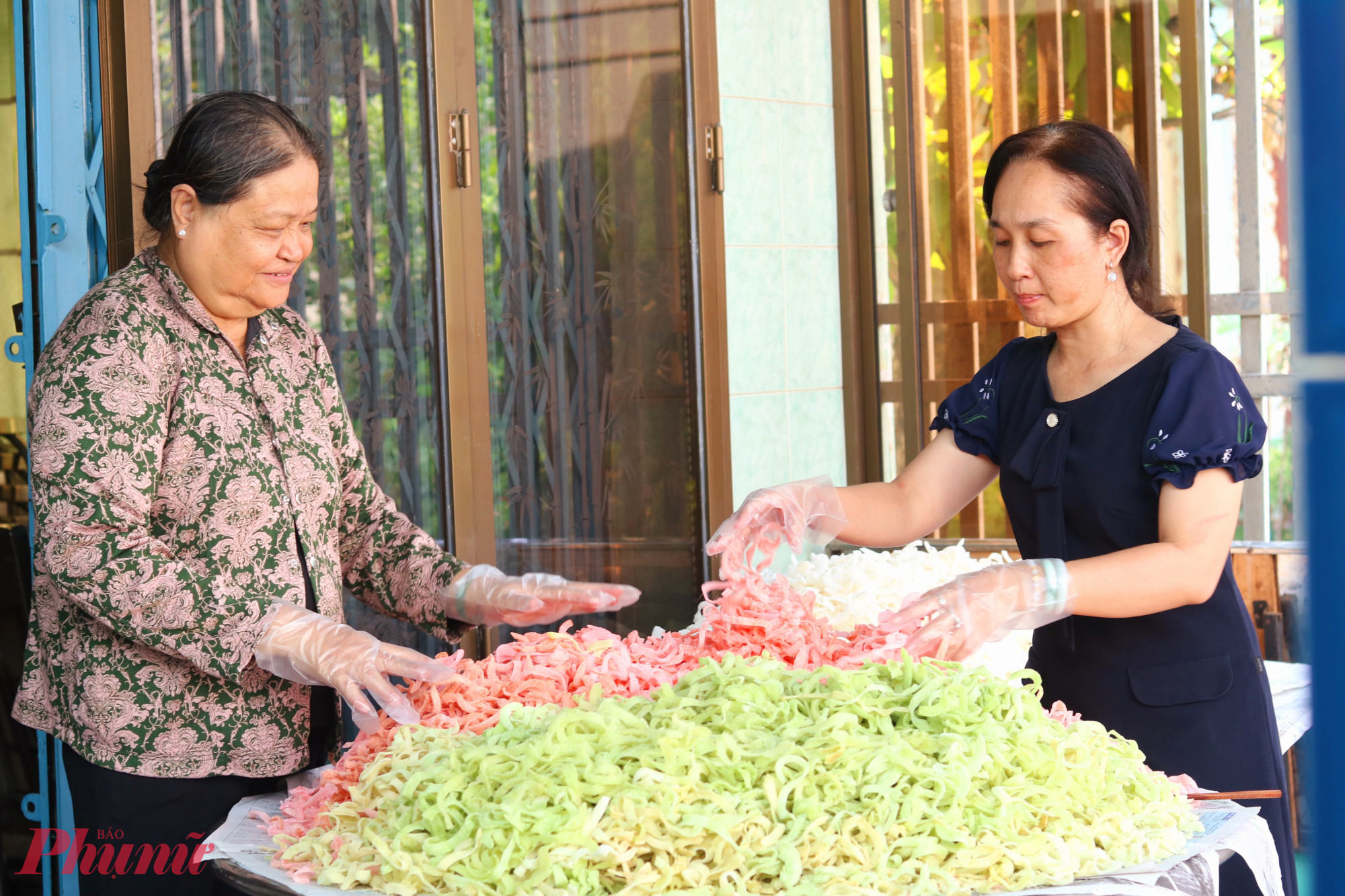 Bà Nguyễn Thị Bạch Tuyết (bìa trái) đã miệt mài góp sức làm mứt tết tặng người lao động xa quê trong nhiều năm qua - Ảnh: Thảo Nguyên 