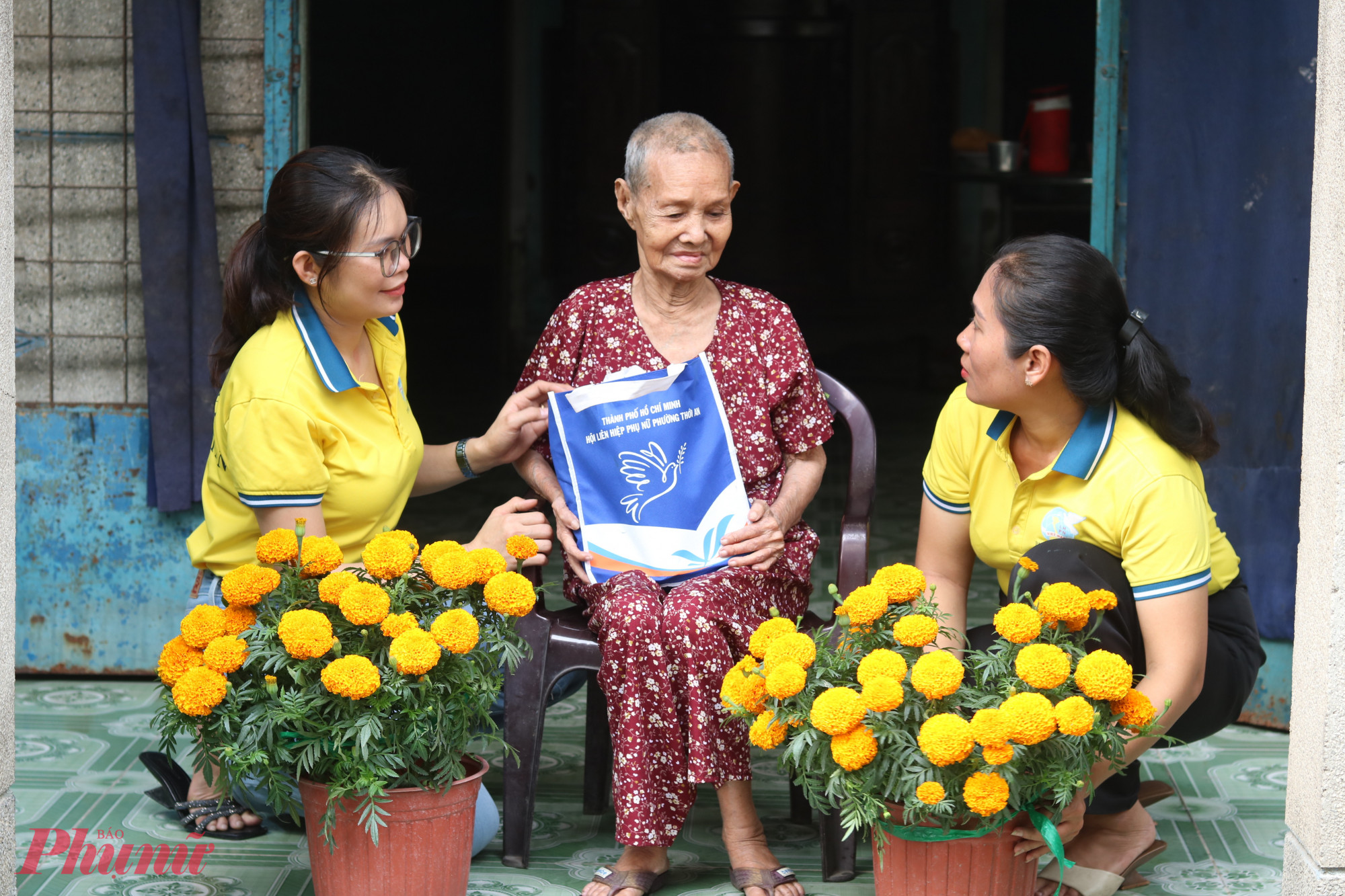 Chị Nguyễn Thị Thúy Vân – Chi hội trưởng Chi hội Phụ nữ khu phố 48, phường Thới An (bìa phải) và chị Hoàng Thị Nhung – hội viên phụ nữ khu phố 48 (bìa trái) cùng chở hoa, quà tết đến nhà bà Phạm Thị Quận tặng - Ảnh: Thảo Nguyên