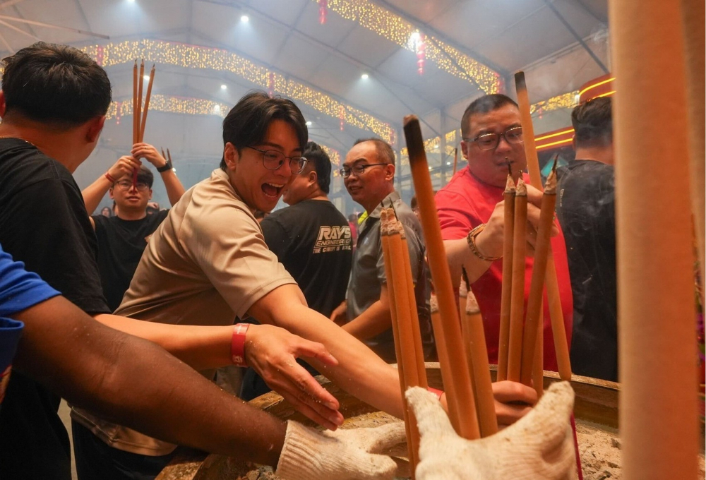 Một người biểu lộ niềm hạnh phúc khi được thắp hương đúng vào lúc nửa đêm tại đền Loyang Tua Pek Kong - Ảnh: AsiaOne/Darren Wong