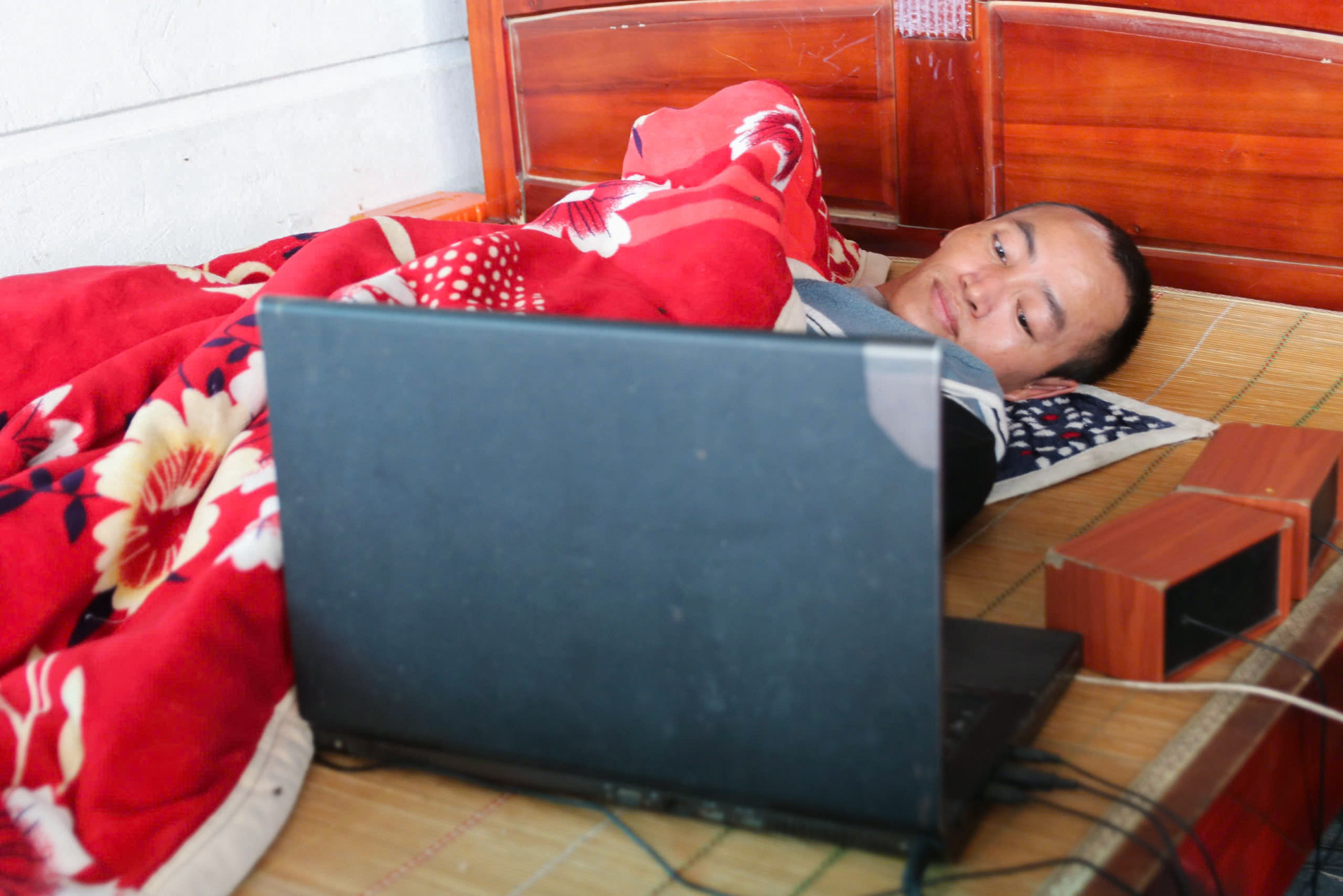 Dù cơ thể chỉ còn cử động được vài ngón tay, anh Kỳ vẫn cố gắng xoay xở làm đủ nghề trên chiếc laptop - Ảnh: Khánh Trung