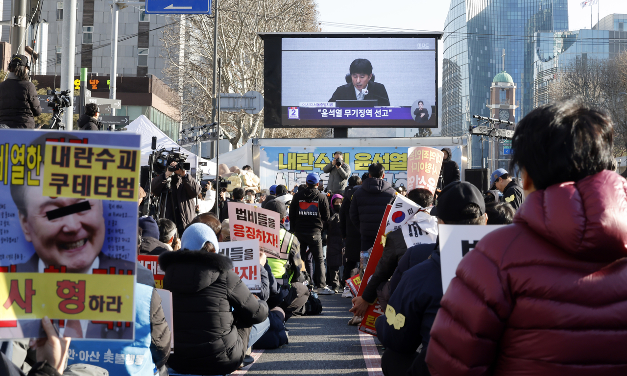 Người dân theo dõi buổi phát sóng trực tiếp gần Tòa án Quận Trung tâm Seoul, Hàn Quốc hôm 19/2 khi tòa án tuyên án cựu Tổng thống Yoon Suk Yeol - Ảnh: Newsis