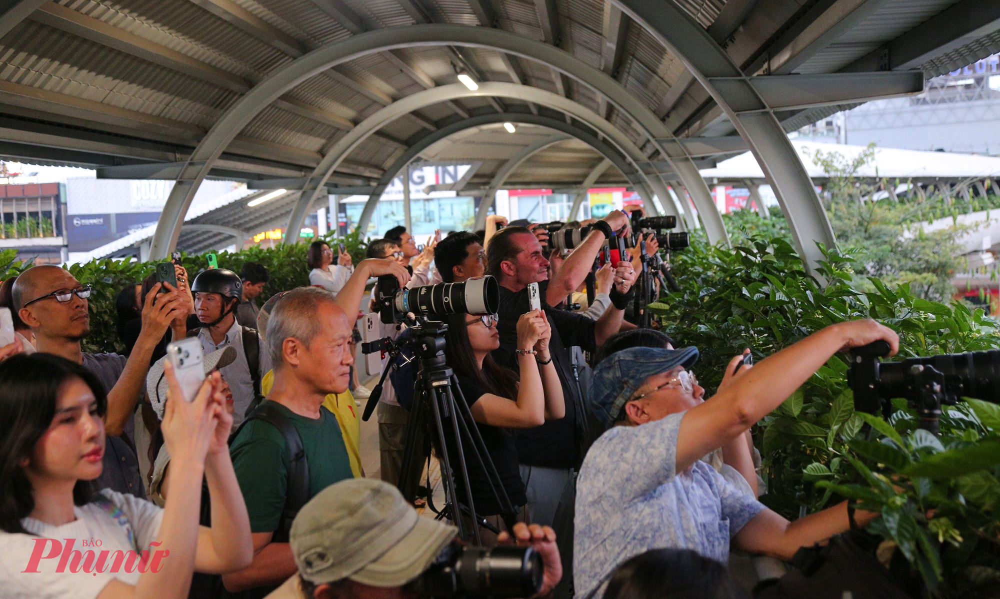 Không khí “săn ảnh” nhộn nhịp như một buổi offline nhiếp ảnh tự phát. Người chỉnh khẩu độ, người kiểm tra pin, người thử trước vài khung hình để căn bố cục sao cho mặt trời tròn đầy nằm đúng vị trí đỉnh cầu. 