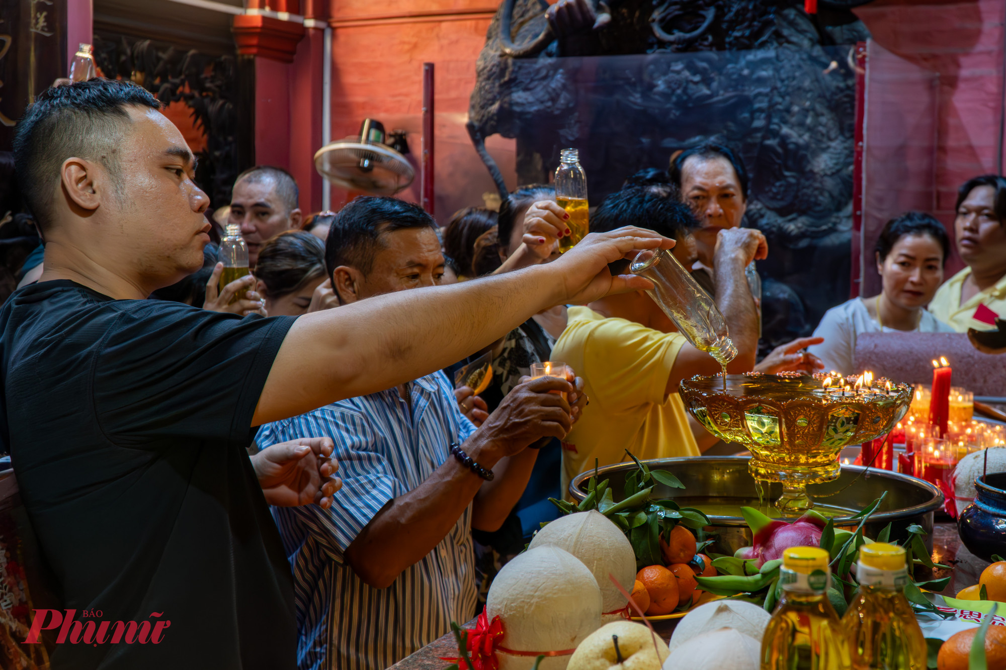 Trong chánh điện, người dân đứng rất đông để chờ đến lượt đổ dầu vào các bát đèn lớn trên bàn thờ để cầu mong bình an, sức khỏe và tài lộc suôn sẻ cho năm mới.