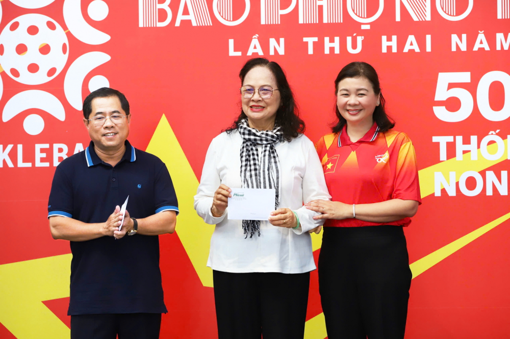 Ông Dương Hồng Nhân (bìa trái) trao kinh phí cho đại diện 15 nữ thanh niên xung phong có hoàn cảnh khó khăn từng tham gia phục vụ, chiến đấu trên tuyến đường 1C tại giải Pickleball Báo Phụ nữ TPHCM năm 2025