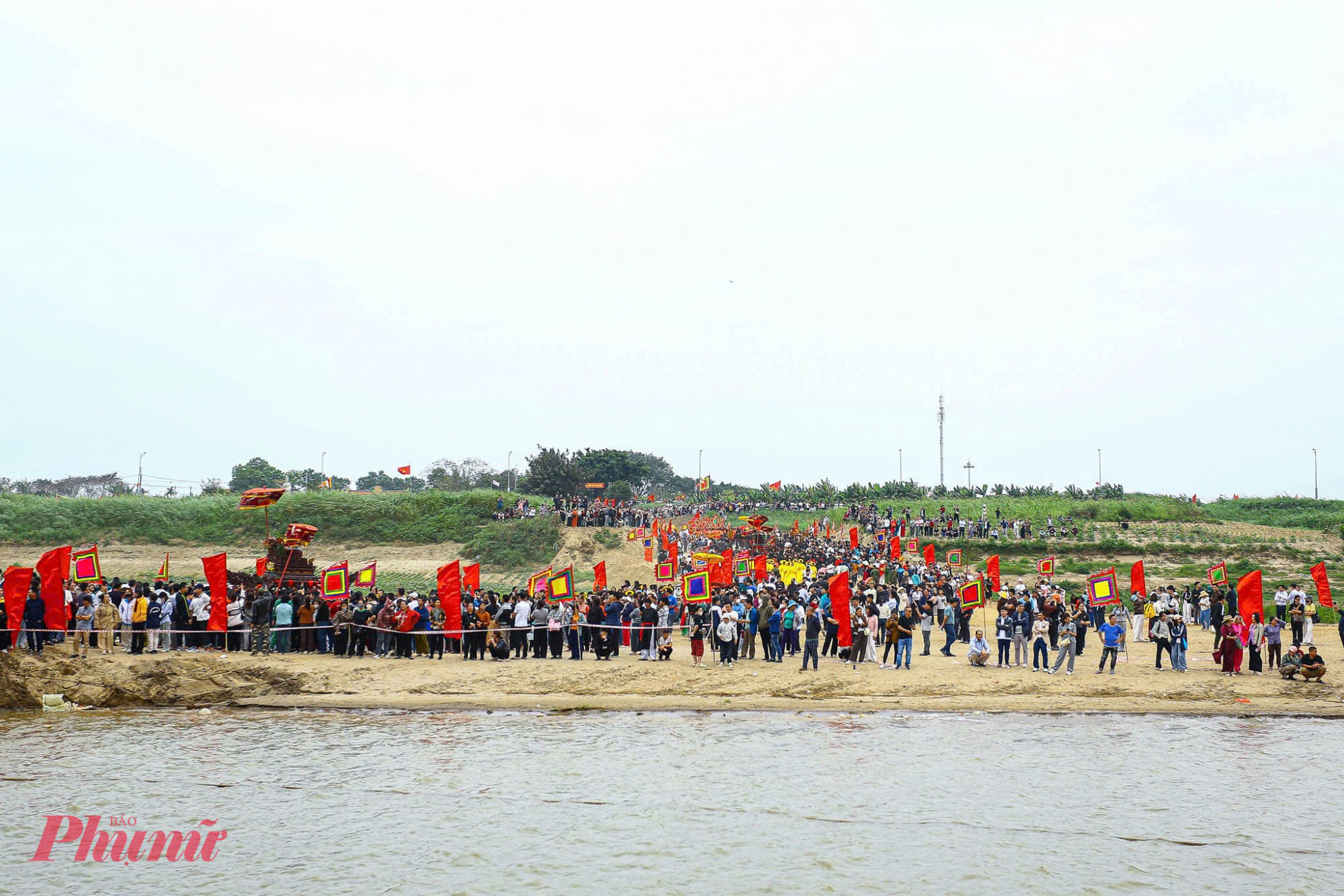 Người dân đứng kín hai bên bờ sông Hồng để chứng kiến đoàn rước di chuyển.