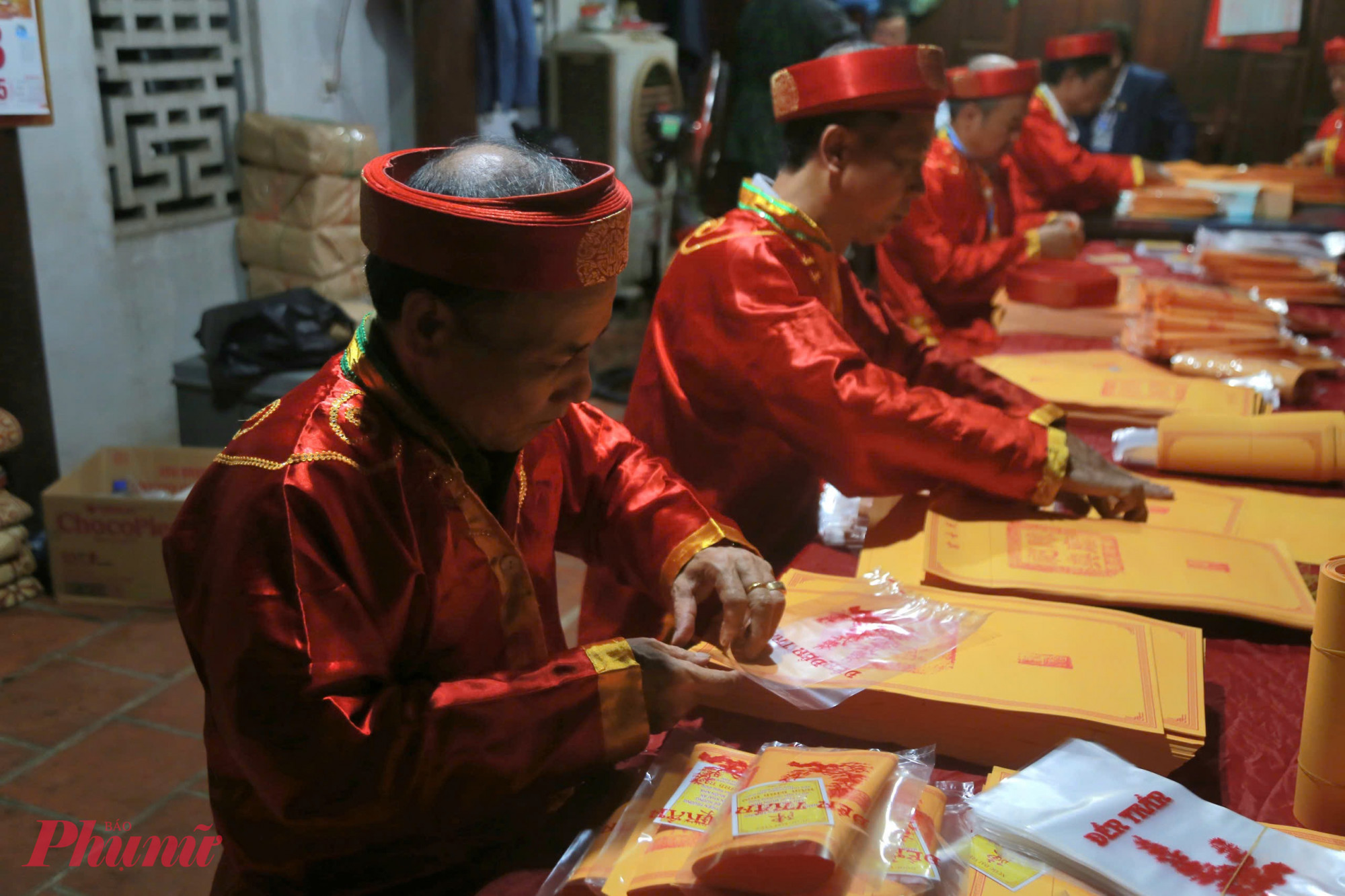 Bên trong khu vực chuẩn bị, thành viên ban tổ chức tất bật sắp xếp, gấp ấn, đóng gói cẩn thận trước giờ phát cho người dân.