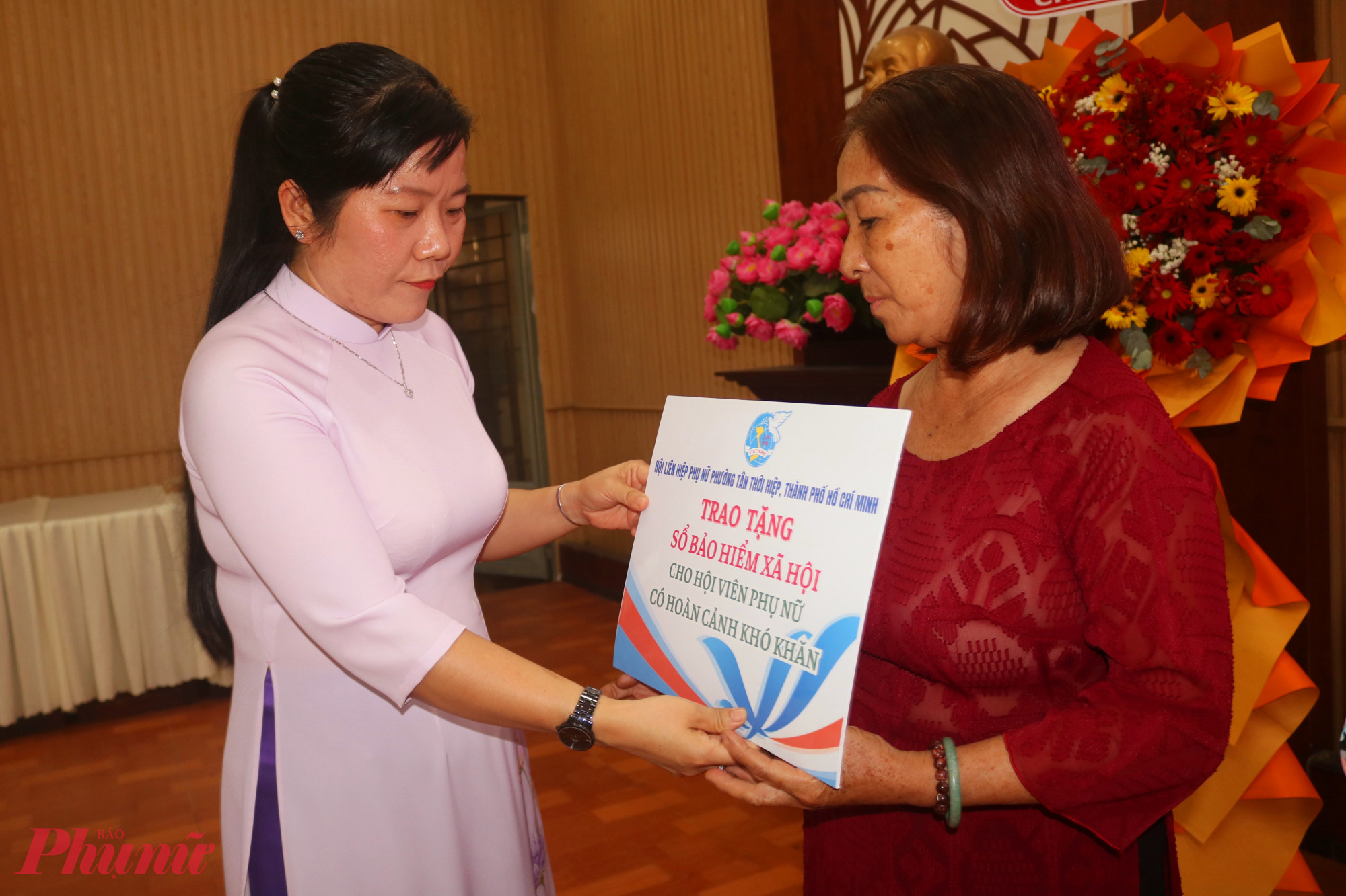 Bà Phạm Thị Mộng Hằng – Phó chủ tịch thường trực Ủy ban MTTQ Việt Nam phường Tân Thới Hiệp, Chủ tịch Hội LHPN phường – trao bảng tượng trưng về việc tặng kinh phí đóng bảo hiểm xã hội tự nguyện cho các dì, các chị - Ảnh: Mẫn Nhi  