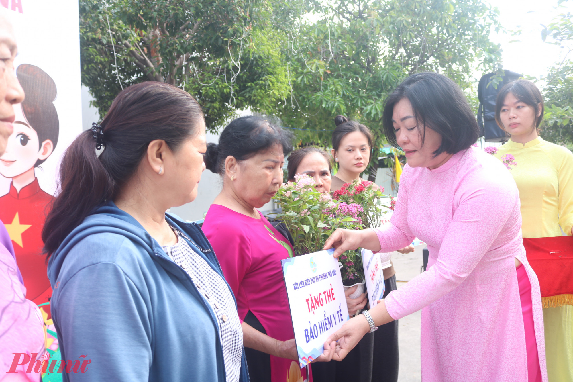 Bà Nguyễn Thị Thanh Luận – Phó chủ tịch Ủy ban MTTQ Việt Nam phường Thủ Đức, Chủ tịch Hội LHPN phường – trao bảng tượng trưng thẻ bảo hiểm y tế cho các dì, các chị - Ảnh: Mẫn Nhi 