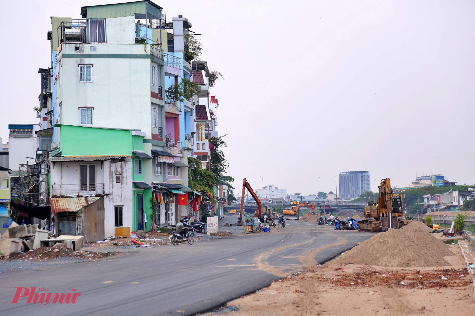 Người dân phường An Hội Tây tranh thủ sửa lại nhà sau khi đường thảm nhựa. Mặt đường thảm nhựa nhưng vẫn
