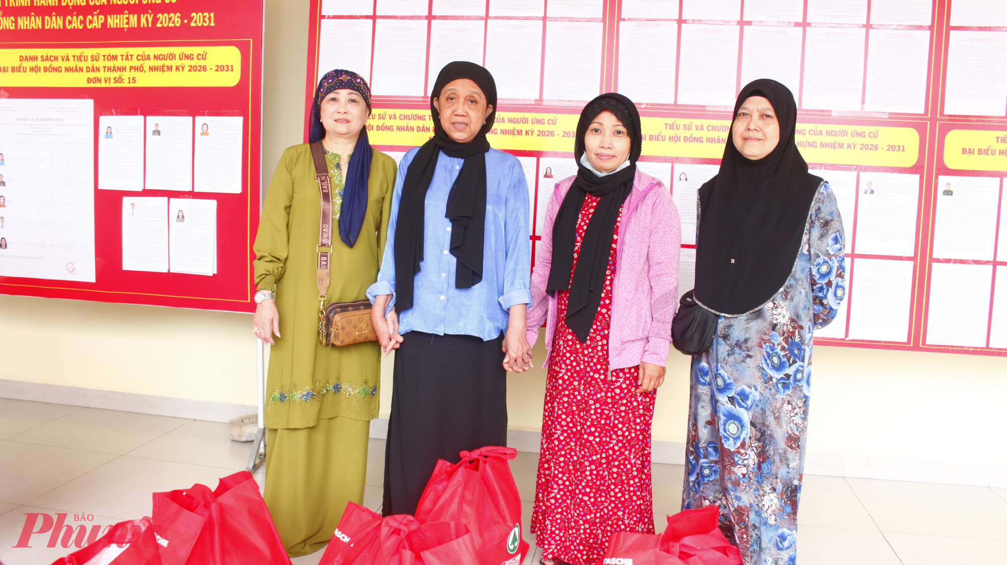 Phụ nữ dân tộc Chăm đến xem thông tin về bầu cử và nhận quà chăm lo vui vẻ ra về