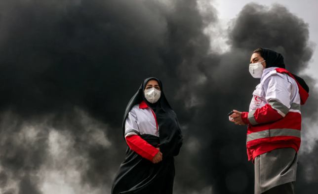  đứng gần những cột khói từ đám cháy từ một cuộc không kích vào nhà máy lọc dầu Shahran ở tây bắc Tehran vào ngày 8/3/2026. (Ảnh của AFP qua Getty Images)Đọc ít hơn