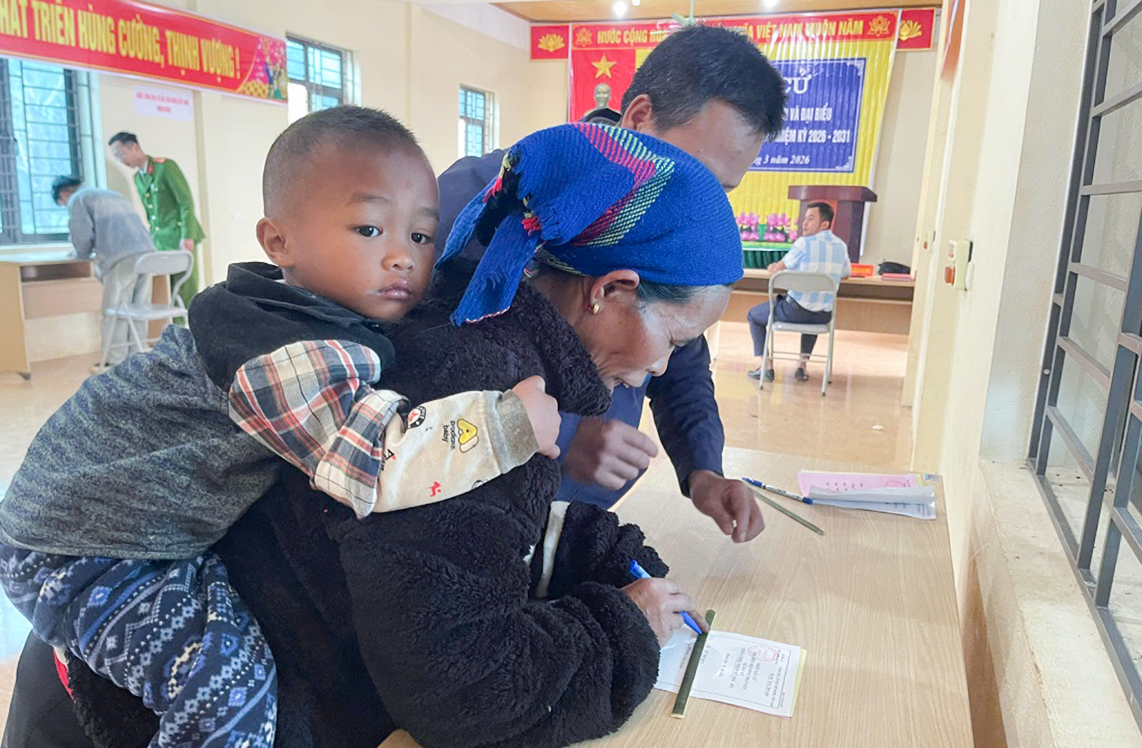 Những đứa trẻ theo lưng mẹ đến điểm bỏ phiếu bầu cử ở bản Cha Nga - Ảnh: P.Thủy