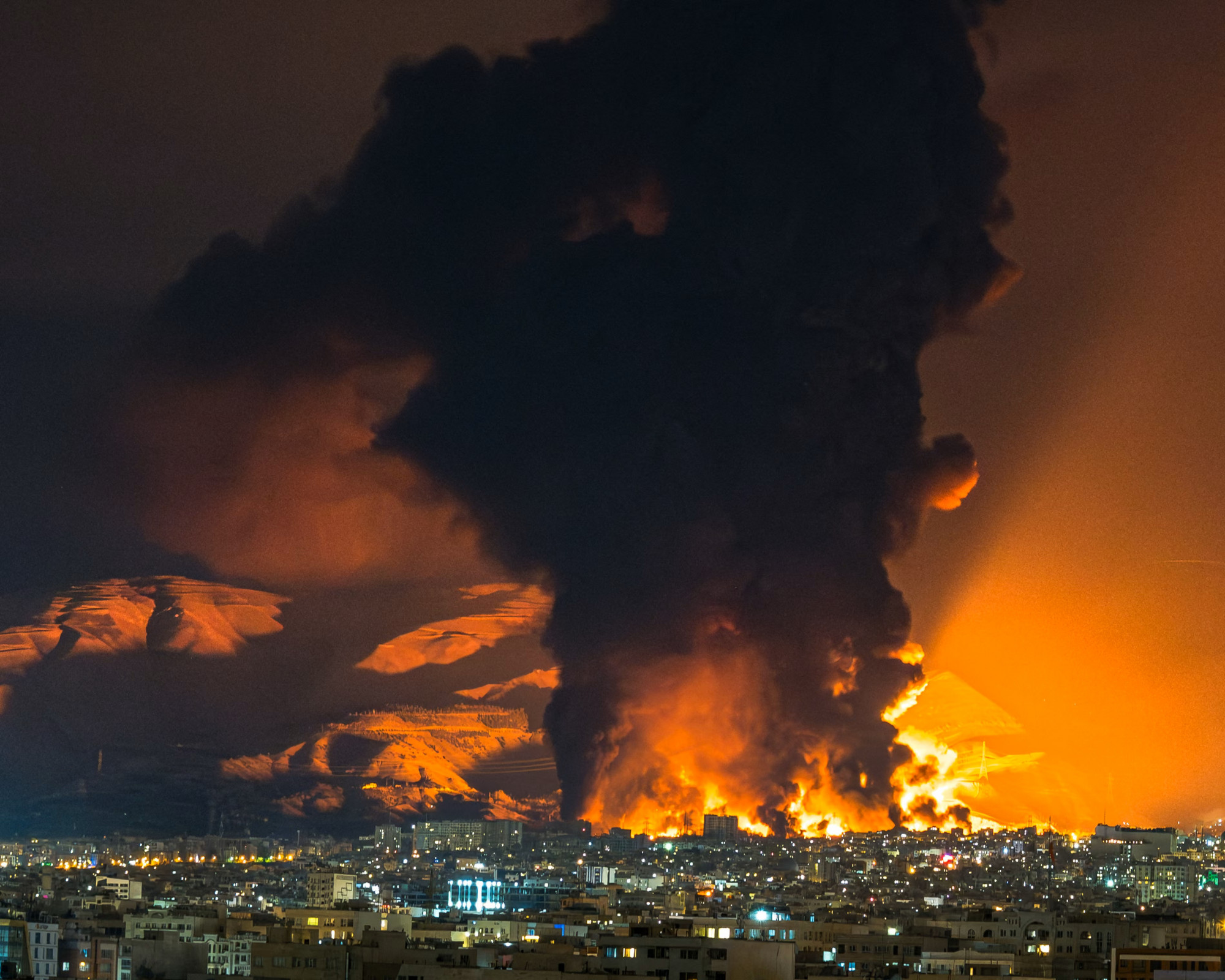 Khói và lửa bốc lên trên Tehran sau một cuộc tấn công vào kho dầu cuối tuần qua - Ảnh: SASAN/Middle East Images/Getty Images