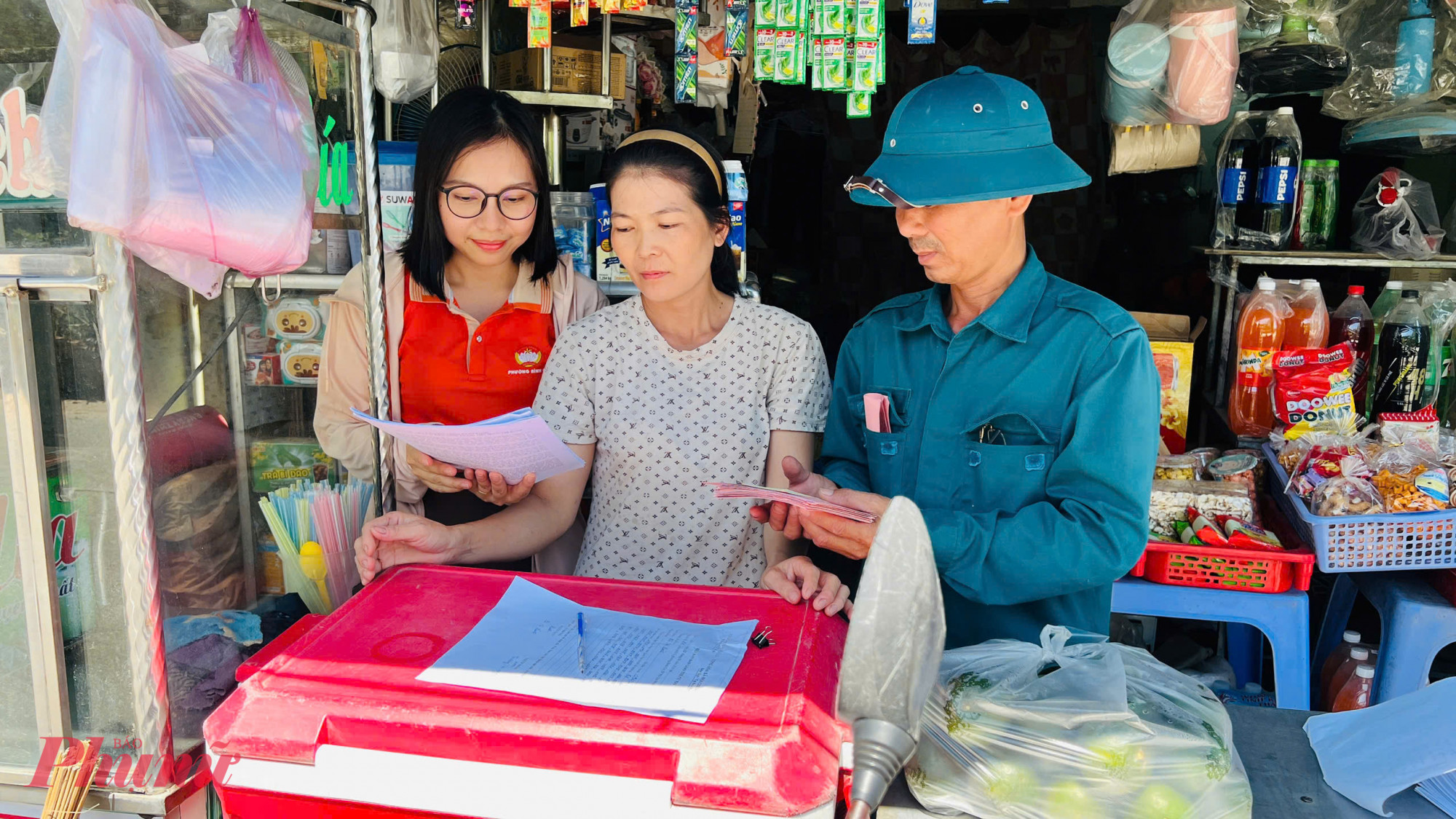 Bà Bồ Thị Cẩm Phương – Chủ tịch Hội LHPN phường Bình Cơ, thành viên Tổ bầu cử số 6, Ban bầu cử số 2 (bìa trái) – gửi thẻ cử tri và tóm tắt tiểu sử các ứng cử viên đến cử tri.