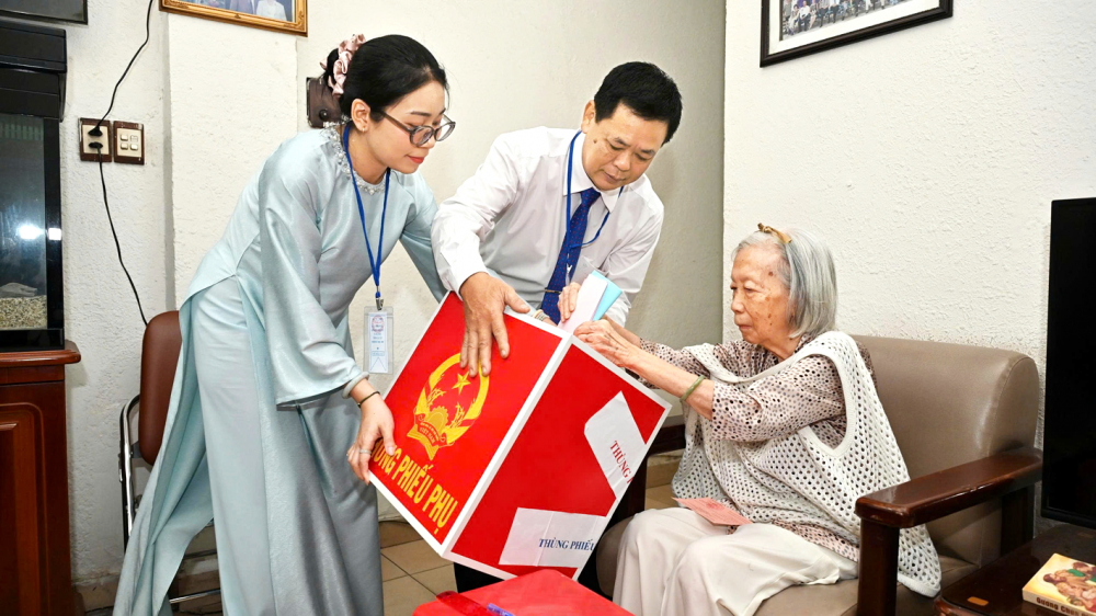 Ông Đoàn Văn Hạnh - Phó bí thư, Trưởng khu phố 12, phường Tân Định, TPHCM - hướng dẫn bà Nguyễn Kim Lan (91 tuổi) bỏ phiếu tại nhà - ẢNH: TRANG THƯ