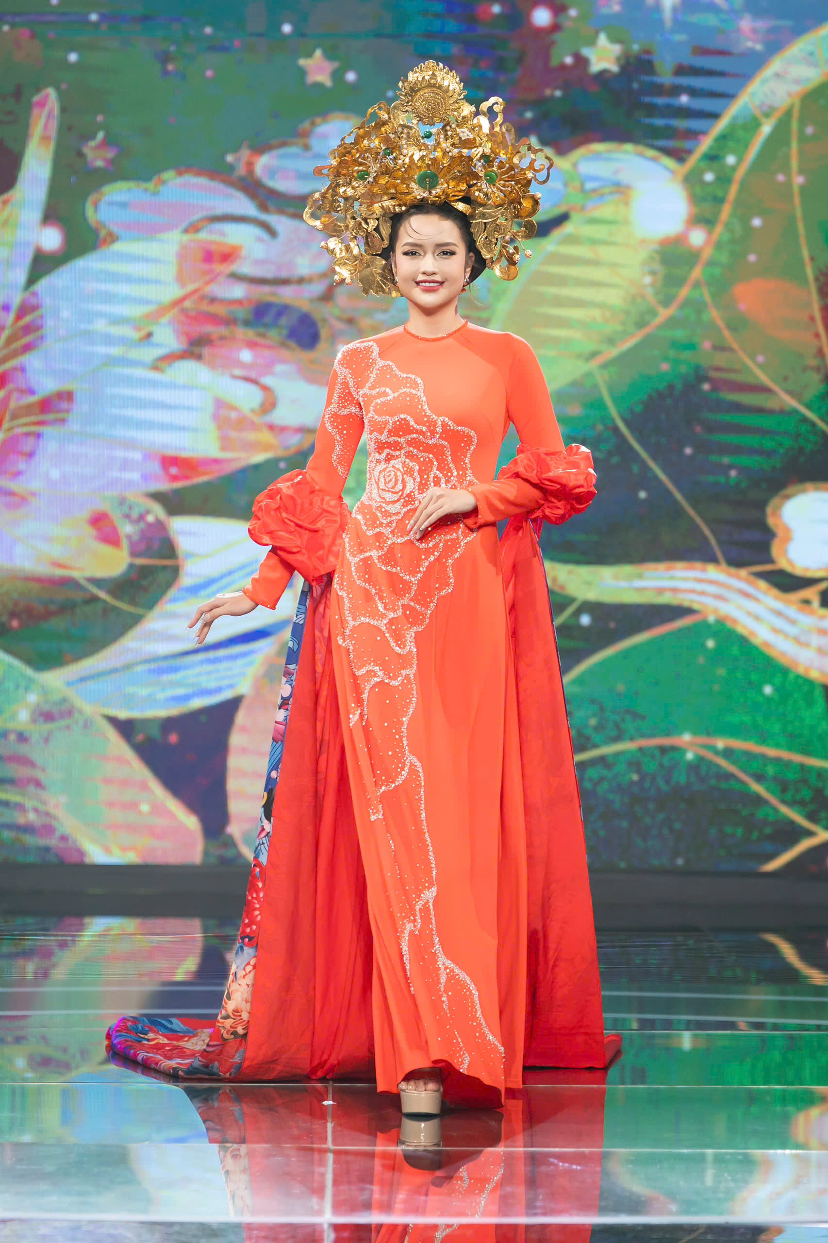 Tham gia chuỗi sự kiện 72 giờ Save The World, lan tỏa thông điệp hòa bình vừa diễn ra tại Việt Nam và nhiều quốc gia trên khắp thế giới, hoa hậu Ngọc Châu diện bộ áo dài màu cam rực rỡ với phom dáng ôm sát, tôn lên đường nét thanh thoát của cơ thể. Phần thân áo được đính kết họa tiết đá lấp lánh tạo hình hoa mềm mại chạy dọc từ vai xuống tà áo, mang lại hiệu ứng thị giác nổi bật dưới ánh đèn sân khấu.