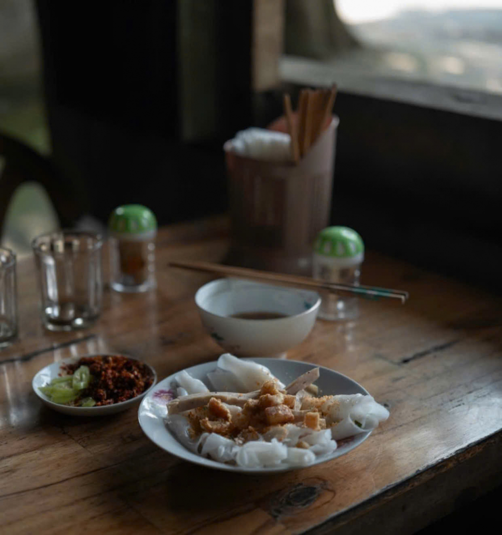 Nằm tại số 32 Hoàng Quốc Việt - một con đường không quá sầm uất, quán bánh ướt O Lan không có bảng hiệu lớn, thậm chí trông khá giản dị với mái ngói bờ rô, bàn ghế nhựa cũ kỹ và sân vườn loang nắng. Nhưng đối với những khách du lịch đã chán với cái xô bồ, đông đúc và ồn ào của thành thị, muốn trải nghiệm một góc nhỏ an yên của thôn quê dân dã thì đây chính là tọa độ lý tưởng. Với giá cả chừng 15k/đĩa bánh ướt thập cẩm , có các loại bánh, chả, tóp mỡ giòn rụm. Bên trên rắc lớp tôm xay, hành phi, ăn kèm với nước mắm ngọt. 