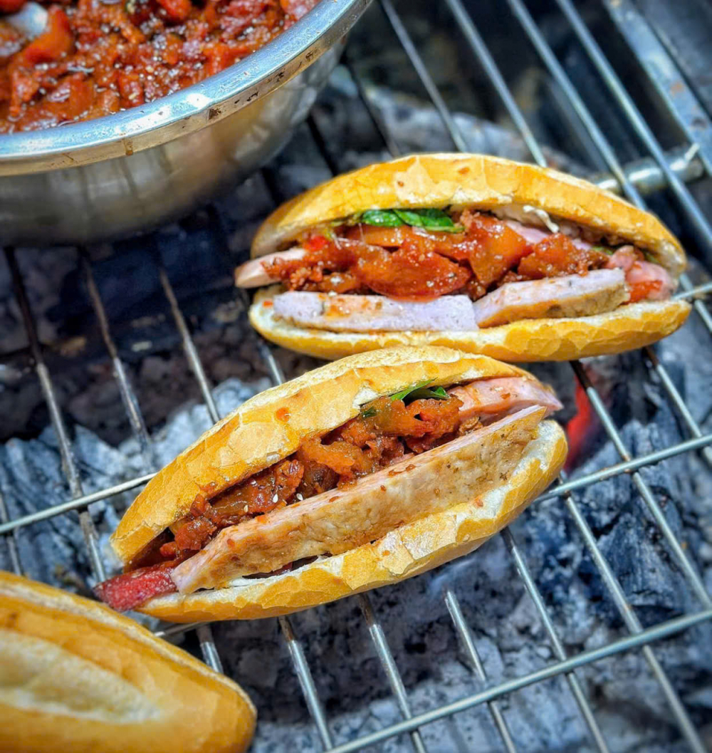 Nằm tại số 14 đường Trần Cao Vân, phường Phú Hội, bánh mì O Tho từ lâu đã trở thành một món ăn không thể thiếu với người dân Huế, và đồng thời là món ăn mà bất kỳ du khách nào cũng nên một lần thưởng thức. Đầu tiên phải kể đến chiếc bánh mì. Dù có kích thước “be bé”, nhỏ nhắn hơn nhiều loại bánh mì khác, nhưng nhân bên trong lại “đầy ụ”, tạo cảm giác no đủ và hấp dẫn ngay từ cái nhìn đầu tiên. Nhân bánh mì đa dạng, từ thịt xíu mềm thơm, thịt nướng đậm đà, lạp xưởng béo ngậy đến nem chua đặc trưng xứ Huế, tất cả đều được chế biến theo công thức riêng của quán.  Tuy nhiên, “linh hồn” thực sự của ổ bánh mì o tho chính là phần nước sốt thịt sền sệt, béo ngậy và thơm lừng. Công thức nước sốt này được O Tho gìn giữ và truyền lại qua nhiều thế hệ, tạo nên hương vị đặc trưng không thể nhầm lẫn. Kết hợp với một chút rau răm the cay, hương vị của bánh mì trở nên cân bằng và kích thích vị giác một cách tuyệt vời.