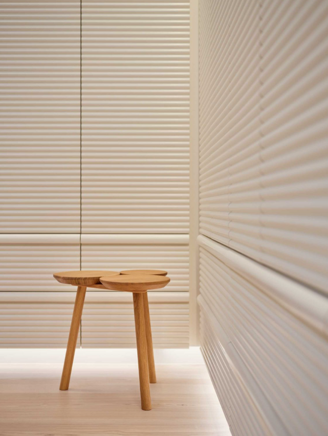 Trên một bức tường, các tấm ốp được gia công bằng máy CNC với các rãnh mềm mại tạo nên kết cấu gợn sóng của bóng đổ. Ảnh: @Aalso Architects, HYCArch.