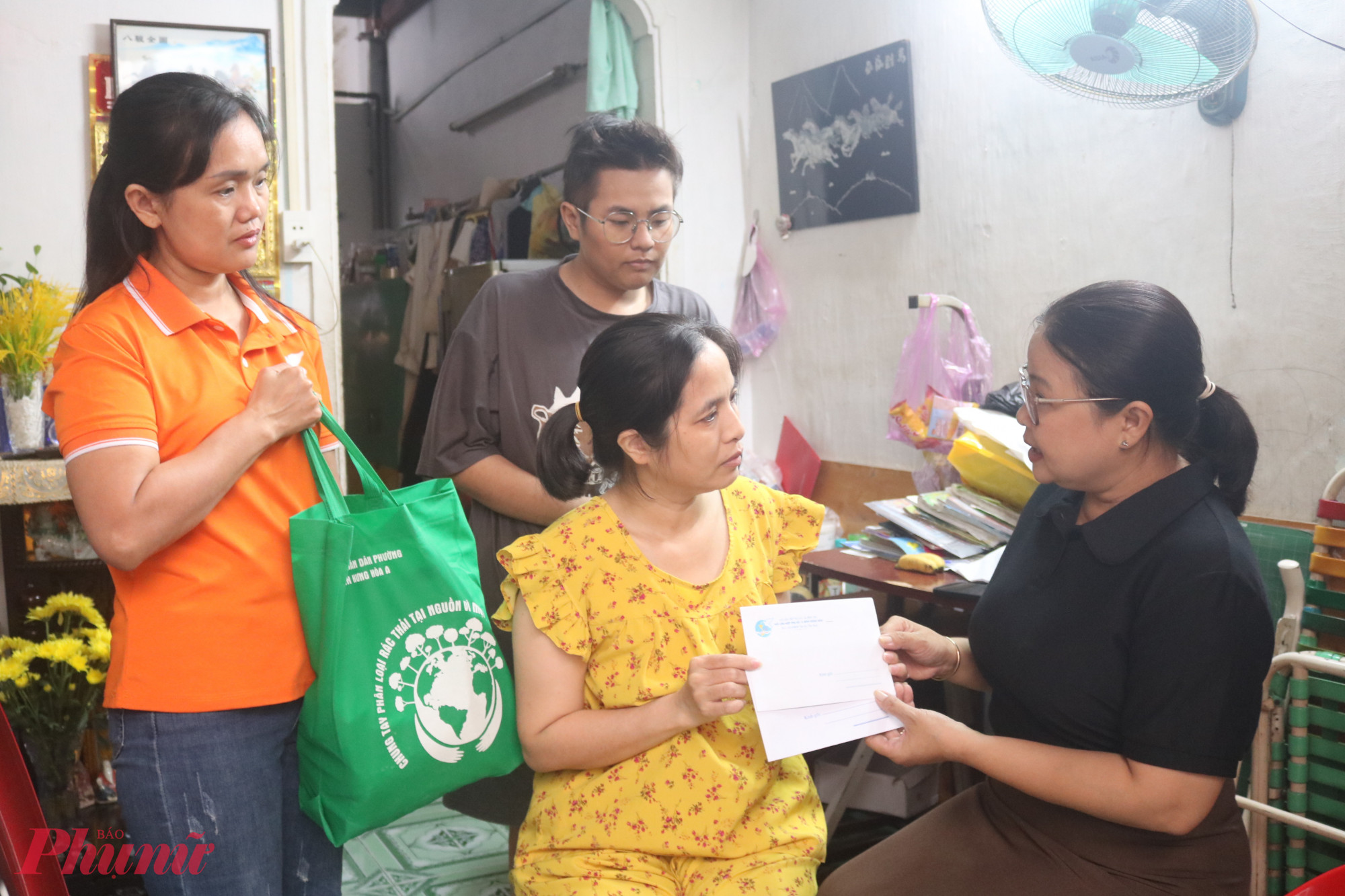Bà Nguyễn Thị Minh Hậu – Phó chủ tịch Ủy ban MTTQ Việt Nam phường Bình Hưng Hòa, Chủ tịch Hội LHPN phường (bìa phải) – tặng quà và động viên chị Luận. Bà nhắn nhũ rằng, khi khó khăn, chị hãy mạnh dạn chia sẻ để hội có giải pháp hỗ trợ kịp thời - Ảnh: Mẫn Nhi
