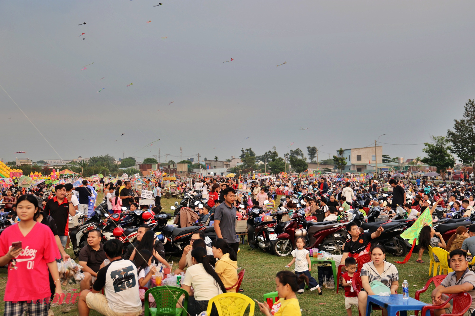 Nhiều gia đình, nhóm bạn trẻ trải bạt ngồi dọc bờ ruộng, vừa hóng gió vừa ngắm diều, tận hưởng không gian thoáng đãng sau một ngày làm việc.