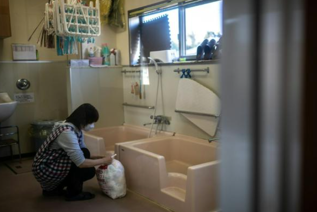 Một nhân viên thu thập một túi tã đã qua sử dụng tại một trường mẫu giáo ở thị trấn Osaki, tỉnh Kagoshima