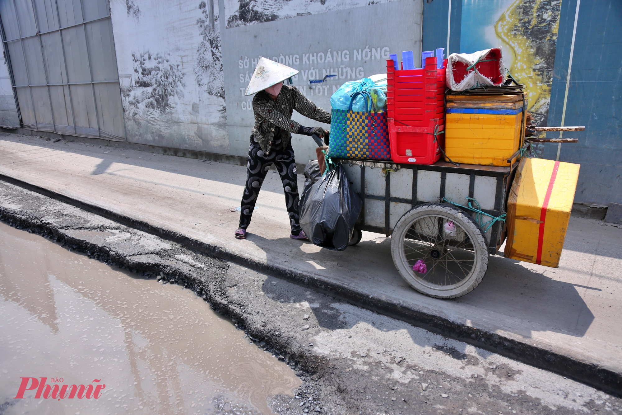 Chị Hồng - người dân sống gần tuyến đường, vừa đẩy xe vừa canh đường vì sợ trượt xuống hố, chia sẻ: “Đường quá xấu nên tụi tôi không dám đi dưới lòng đường. Nhiều hôm phải chạy lên vỉa hè cho an toàn, chứ đi dưới dễ té lắm”.