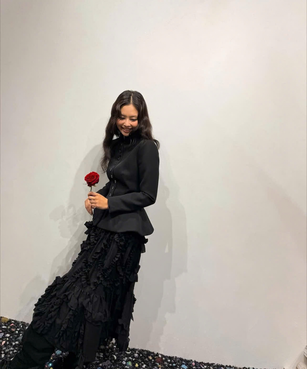 Hoặc trong một bản phối khác, Jennie lại cho thấy cách kết hợp trang phục khá thu vị theo phong cách Monochrome. Nữ ca sĩ lựa chọn một chiếc blazer đen với bề mặt trơn cùng chân váy với thiết kế cách điệu. 