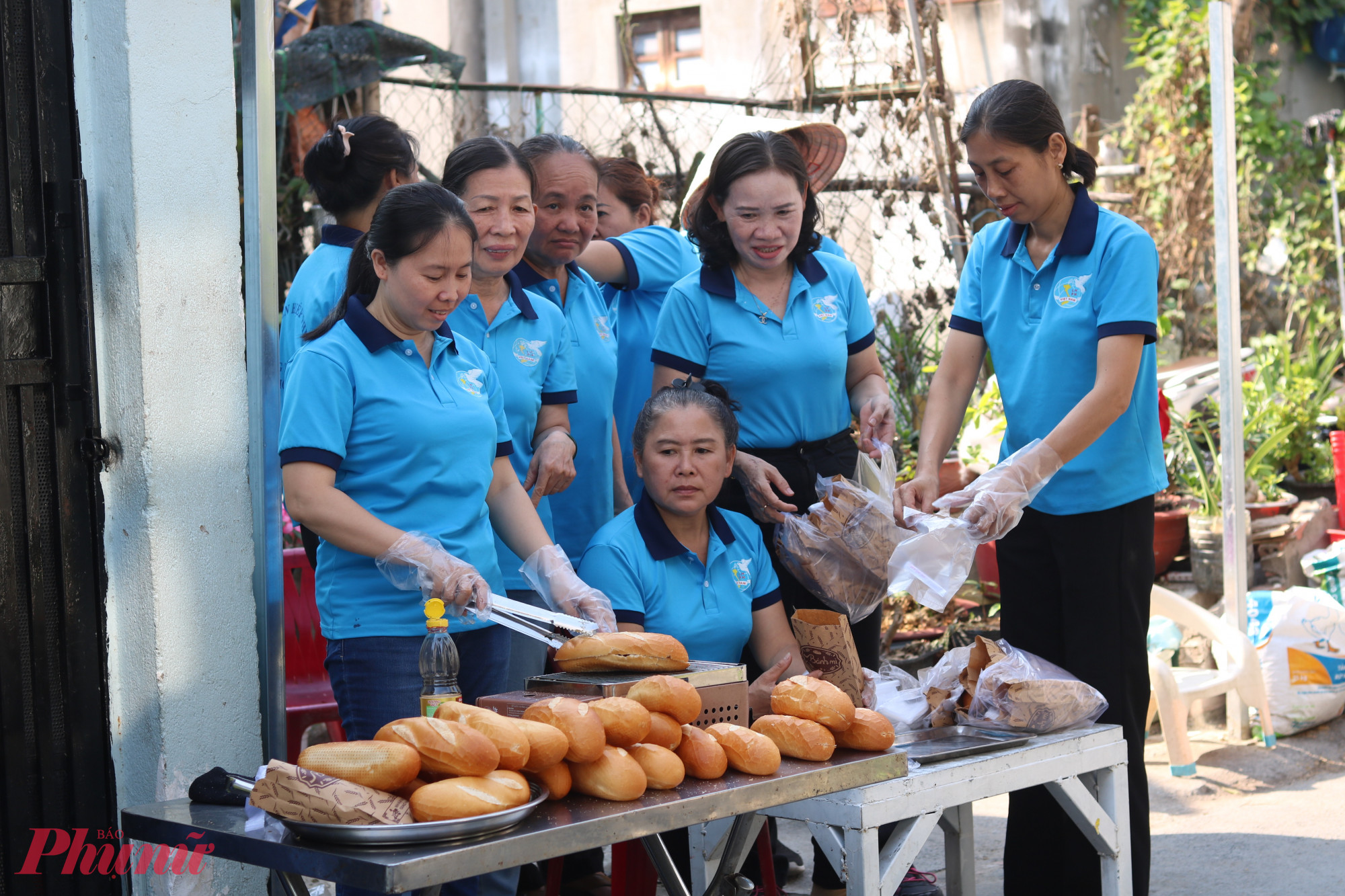 Cùng với việc tặng xe mới cho chị Quý, trong ngày 31/3, cụm thi đua 1, trực thuộc Hội LHPN phường Tân Thới Hiệp cũng làm 250 ổ bánh mì tặng người lao động có hoàn cảnh khó khăn. Trong ảnh là chị Quý (ảnh trên) và các chị em chuẩn bị những ổ bánh mì nóng giòn trước khi trao tay người cần - Ảnh: Mẫn Nhi