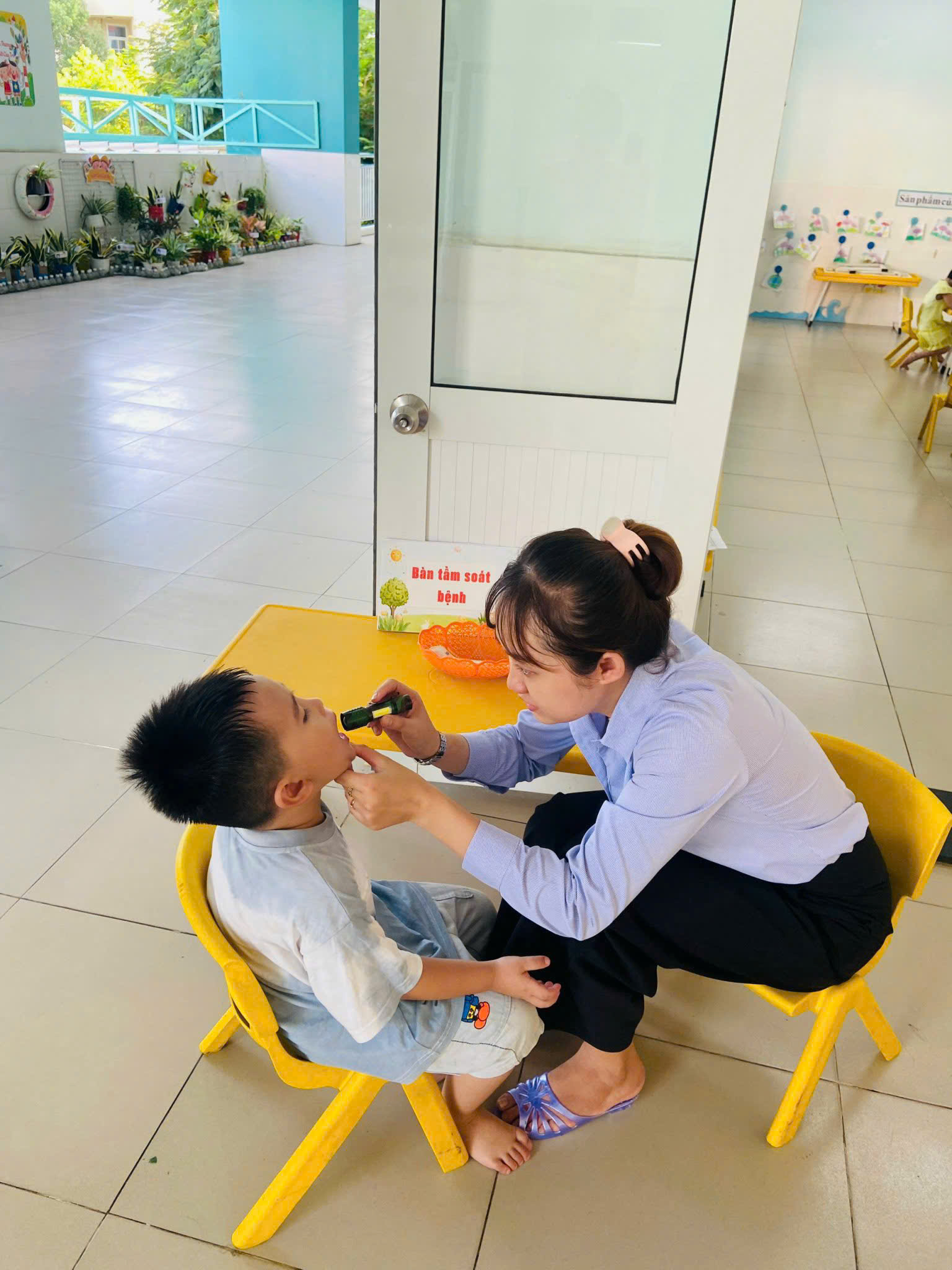 Giáo viên Trường mầm non Tân Phong (phường Tân Hưng) kiểm tra thân nhiệt cho trẻ trước giờ vào lớp - Ảnh: T.T.