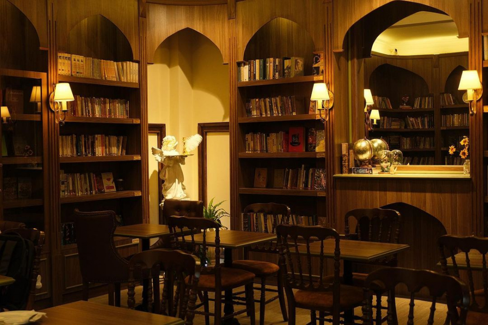 Bibli Library Café (42/5 Hồ Hảo Hớn, phường Cầu Ông Lãnh) là không gian lý tưởng cho những người yêu sách và cà phê. Với không gian rộng rãi trải dài 2 tầng lầu, quán gây ấn tượng từ cái nhìn đầu tiên với cửa kính viền đỏ, như một lời gợi nhắc về những buồng điện thoại công cộng xưa. Phong cách cổ điển với gam màu vàng, nâu chủ đạo, hòa lẫn vào sự tươi mát của tự nhiên và cây cối.  Kệ sách được sắp xếp kín tường, tạo cảm giác như bước vào một thư viện cổ kính thu nhỏ với hơn 300 đầu sách. Bibli Library Café chắc chắn sẽ là địa điểm lý tưởng cho những ai muốn trải nghiệm một không gian yên tĩnh để đọc sách và làm việc, hay đang loay hoay tìm kiếm nguồn cảm hứng để nâng cao tinh thần và năng lượng trong cuộc sống.